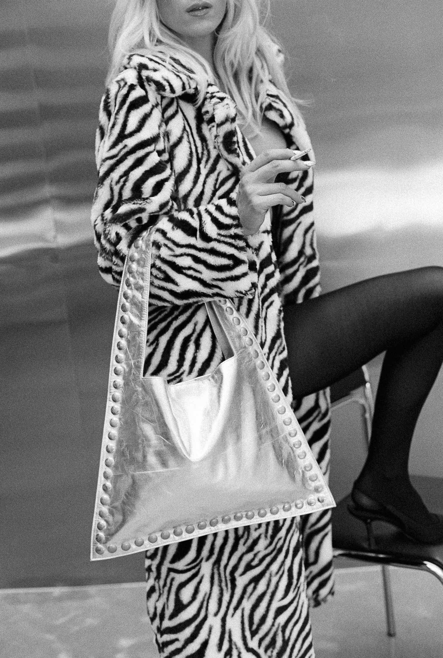 Stylish zebra print coat paired with studded metallic handbag in black and white composition.