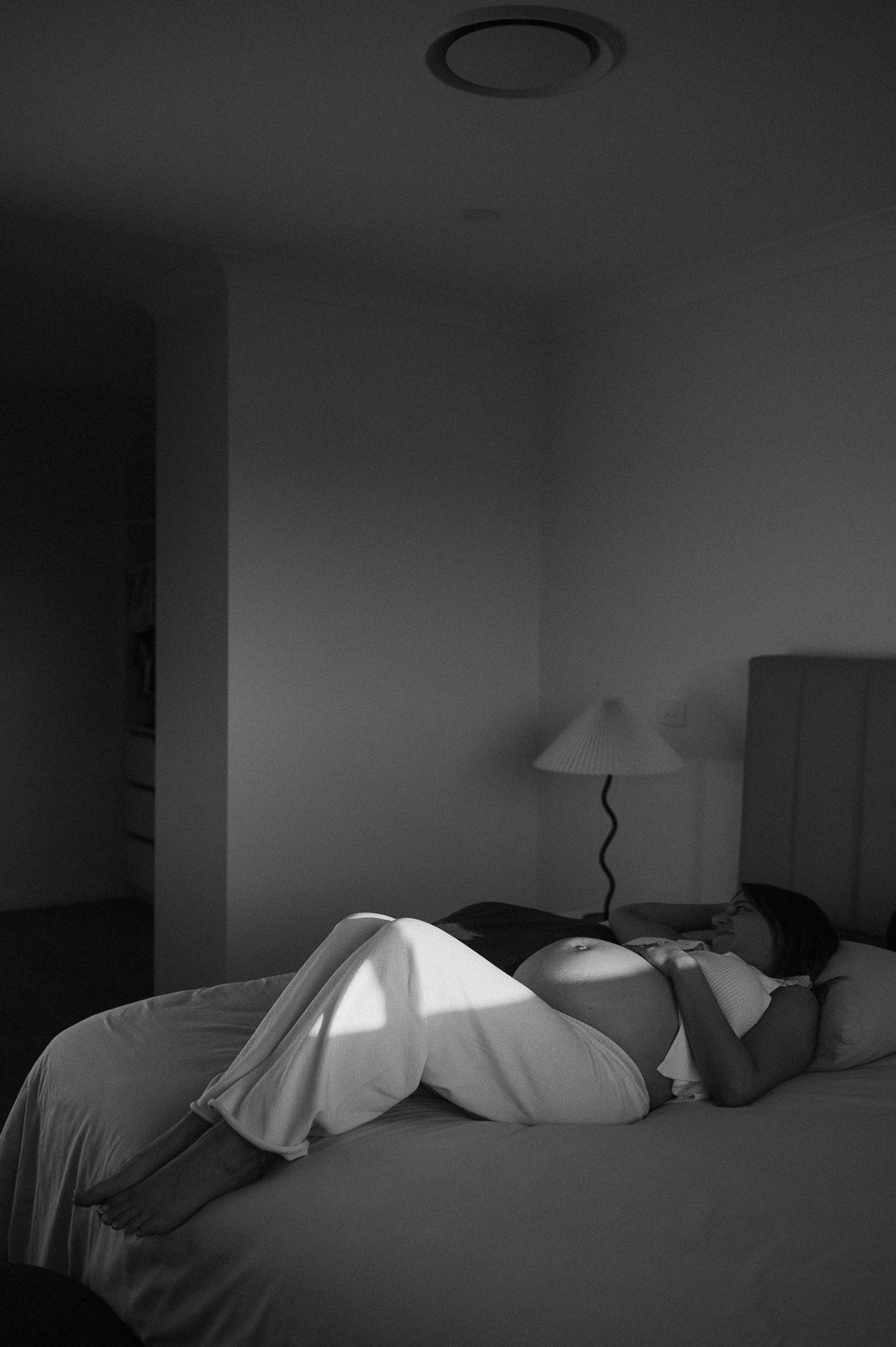 Moody black and white photo of unmade bed with dramatic lighting.