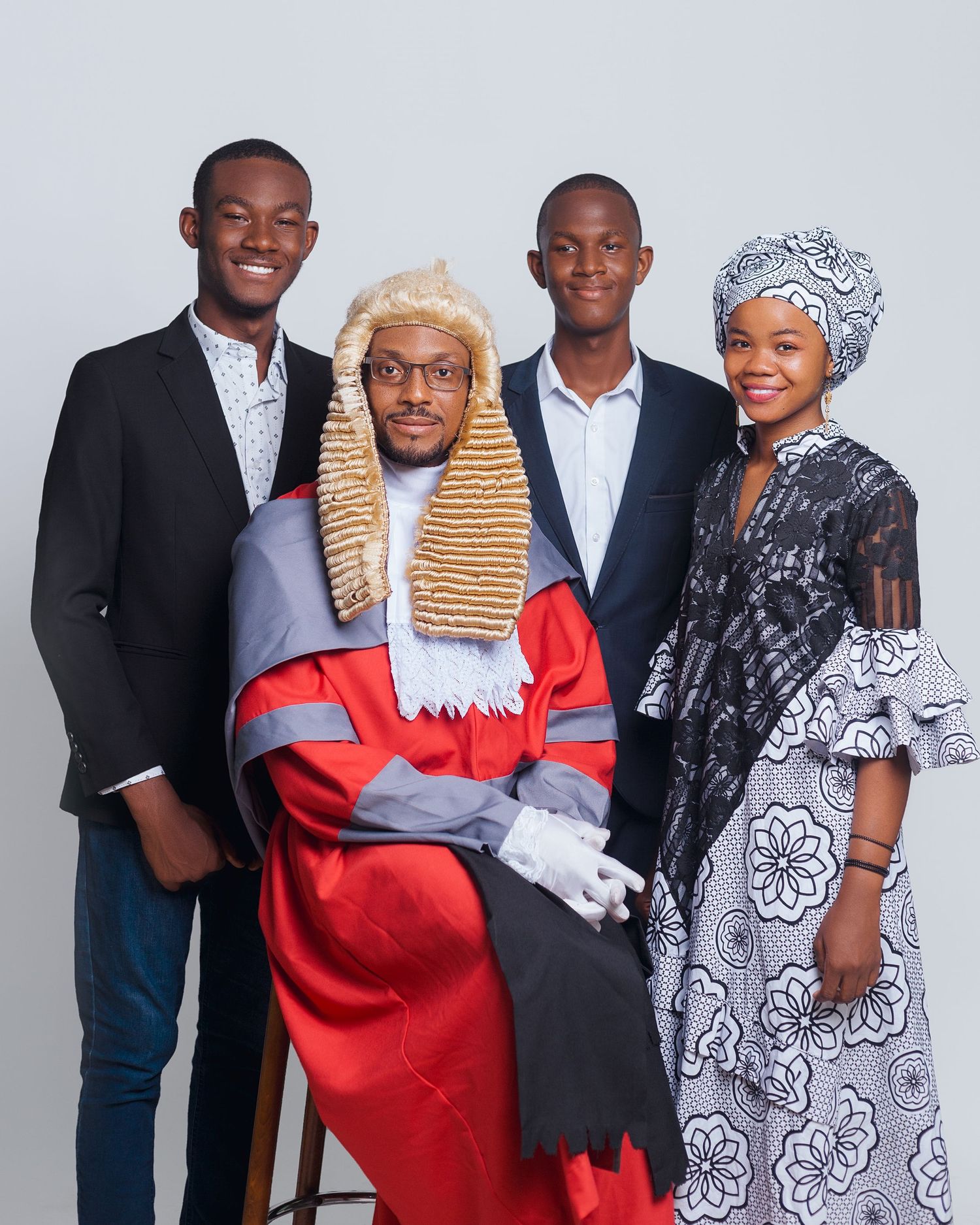 A group portrait show people standing together where one wears traditional legal robes and wig while others wear formal attire.