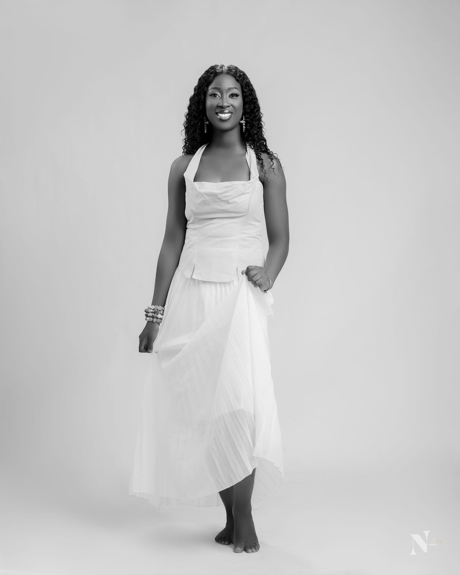 Woman in elegant white sundress poses in black and white photo series showing dynamic movement and style.
