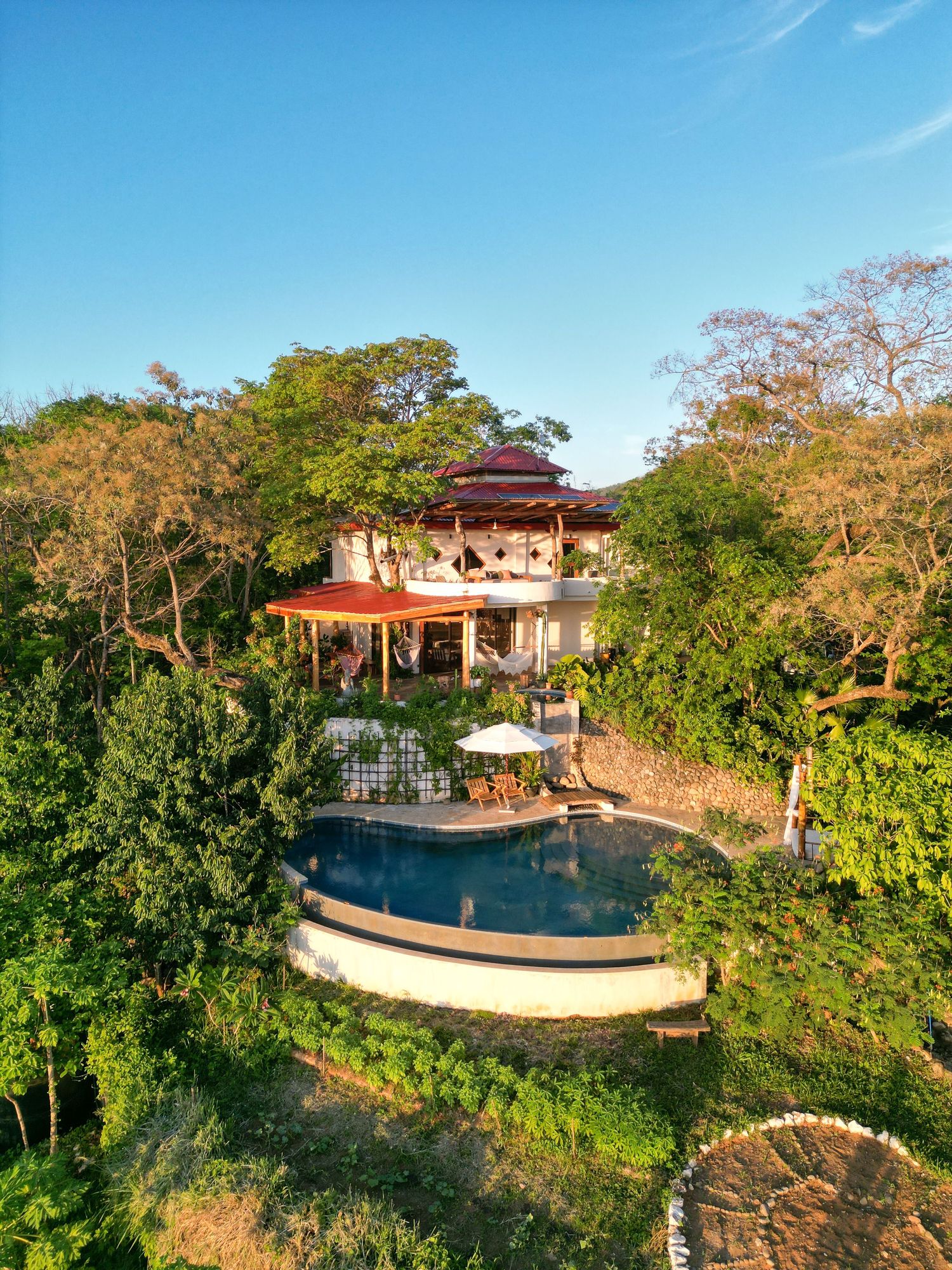 Luxury resort pool area with panoramic views of tropical landscape and gazebo overlooking the scenery.
