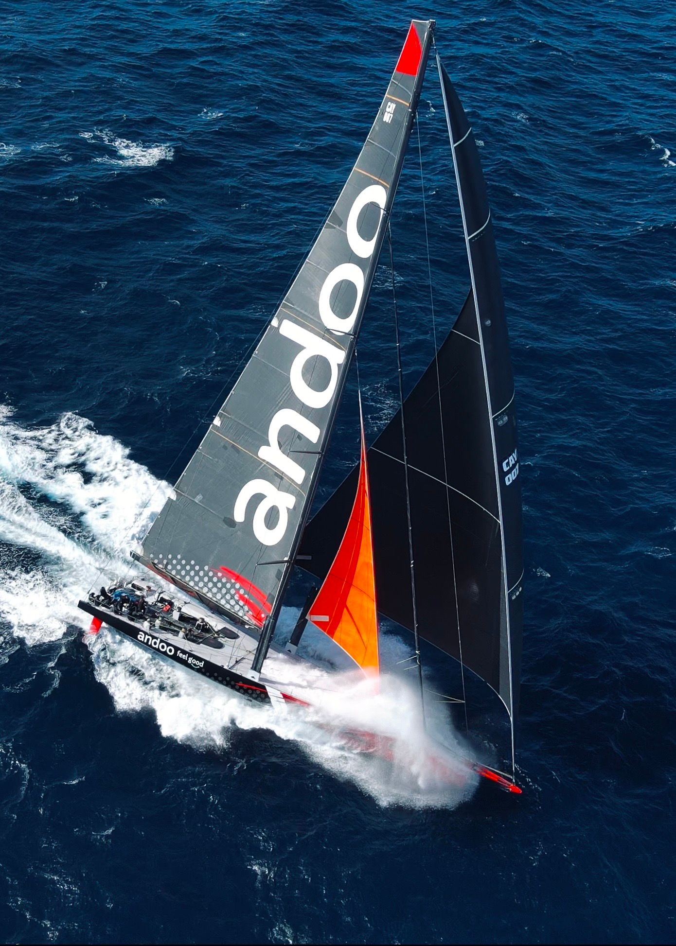 Racing sailboat cutting through blue ocean water with dramatic spray.