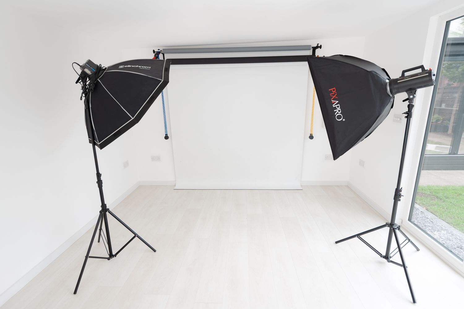 Professional photography lighting softbox setup with black and white studio gear against white backdrop and windows.