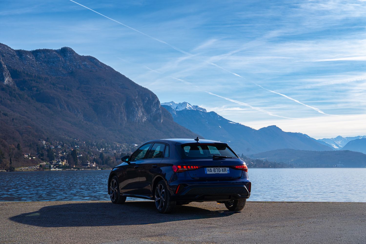 Black Audi RS6 wagon parked against scenic mountain lake backdrop with blue skies and dramatic landscapes.