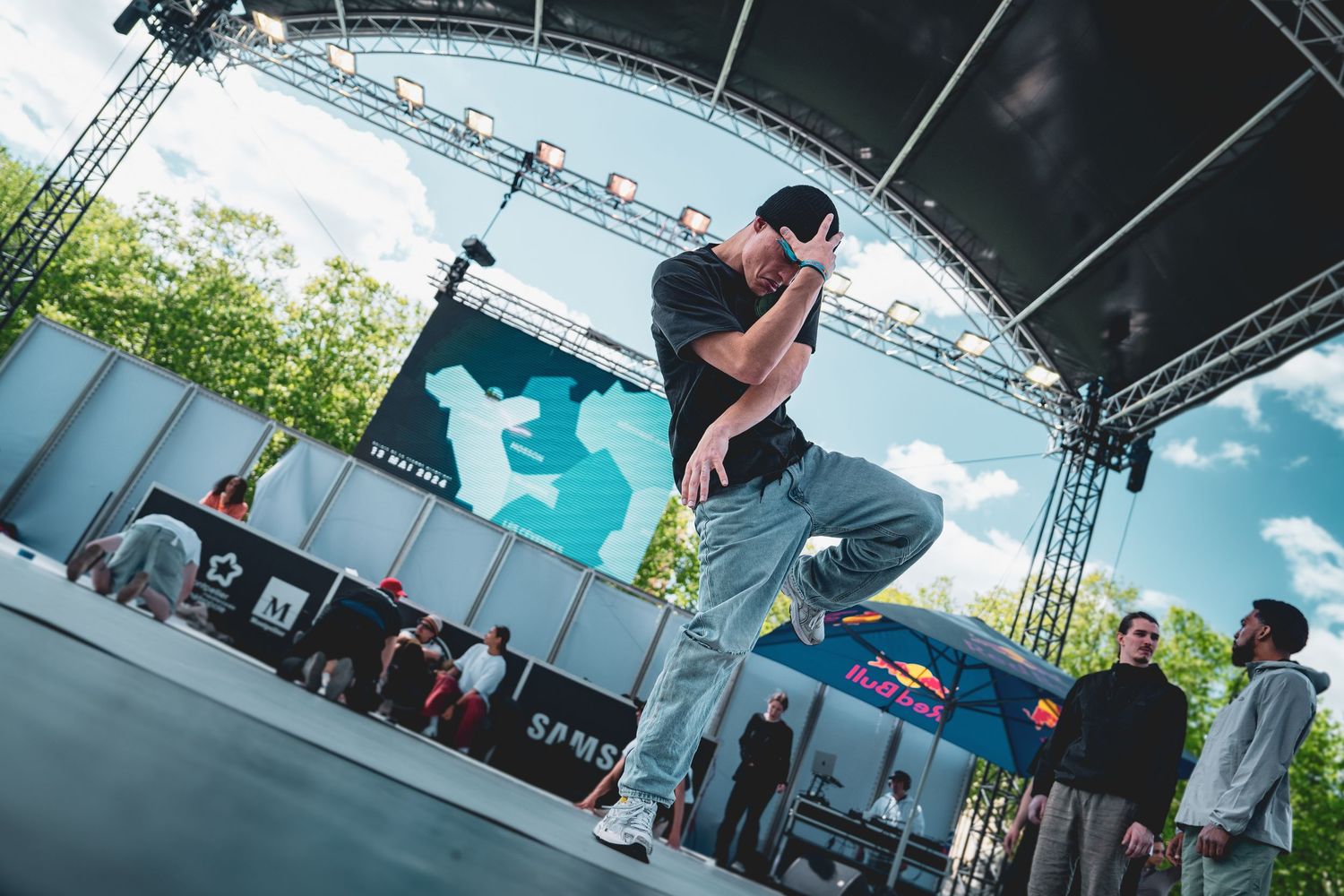 Performer on outdoor festival stage with blue sky backdrop.