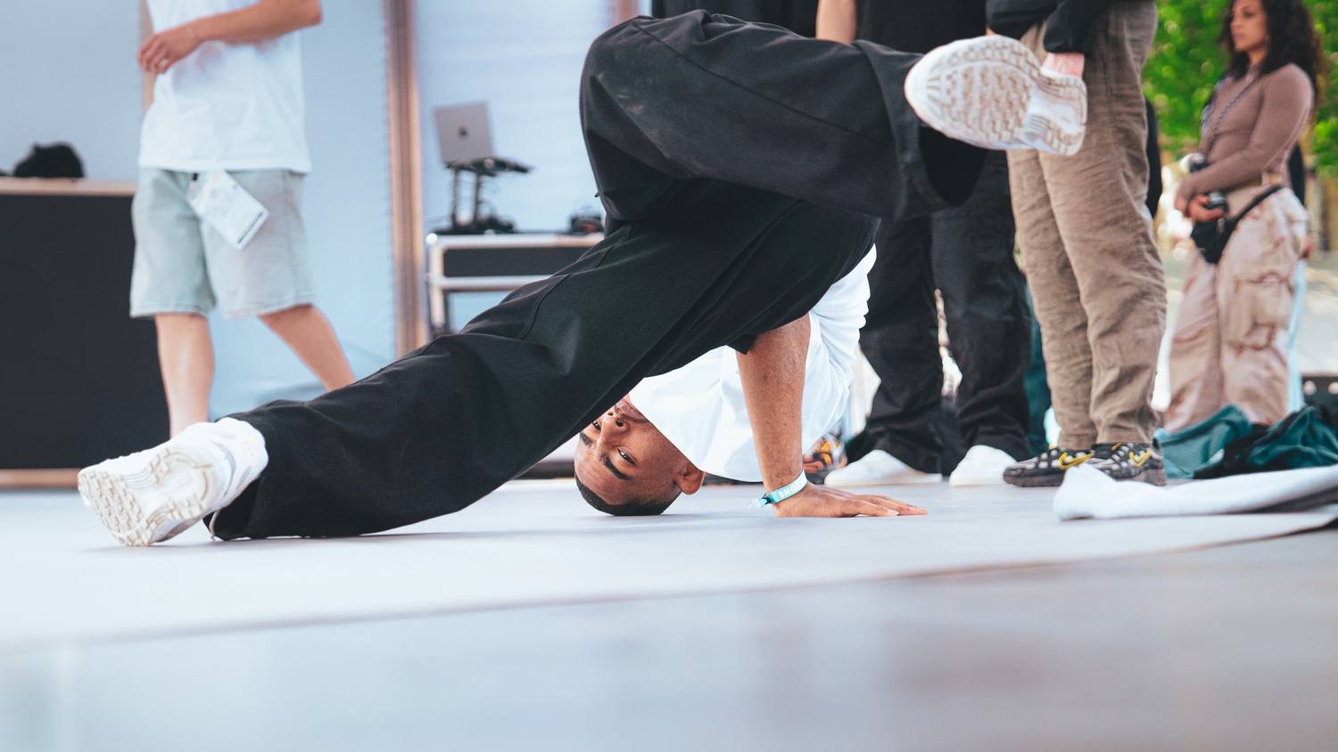 Dancers perform dynamic breakdancing moves on a white floor during an energetic street dance competition.
