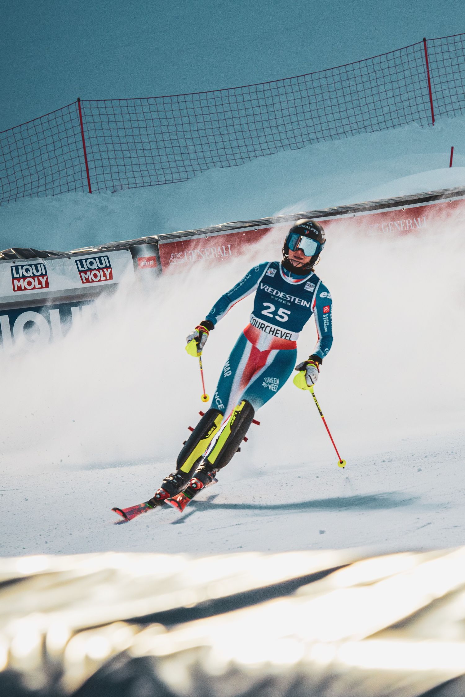 Alpine skier in racing gear carves through snowy slalom course during competitive downhill competition.