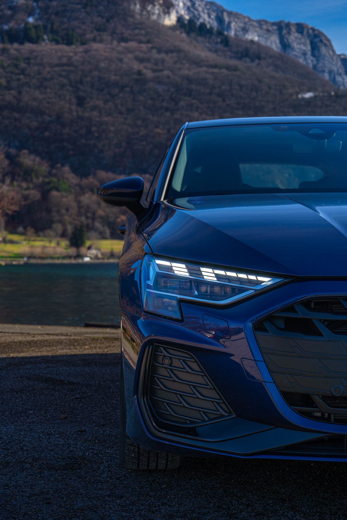 Close-up view of a sleek blue Chevrolet Corvette front end showing modern LED headlights and aggressive styling details.