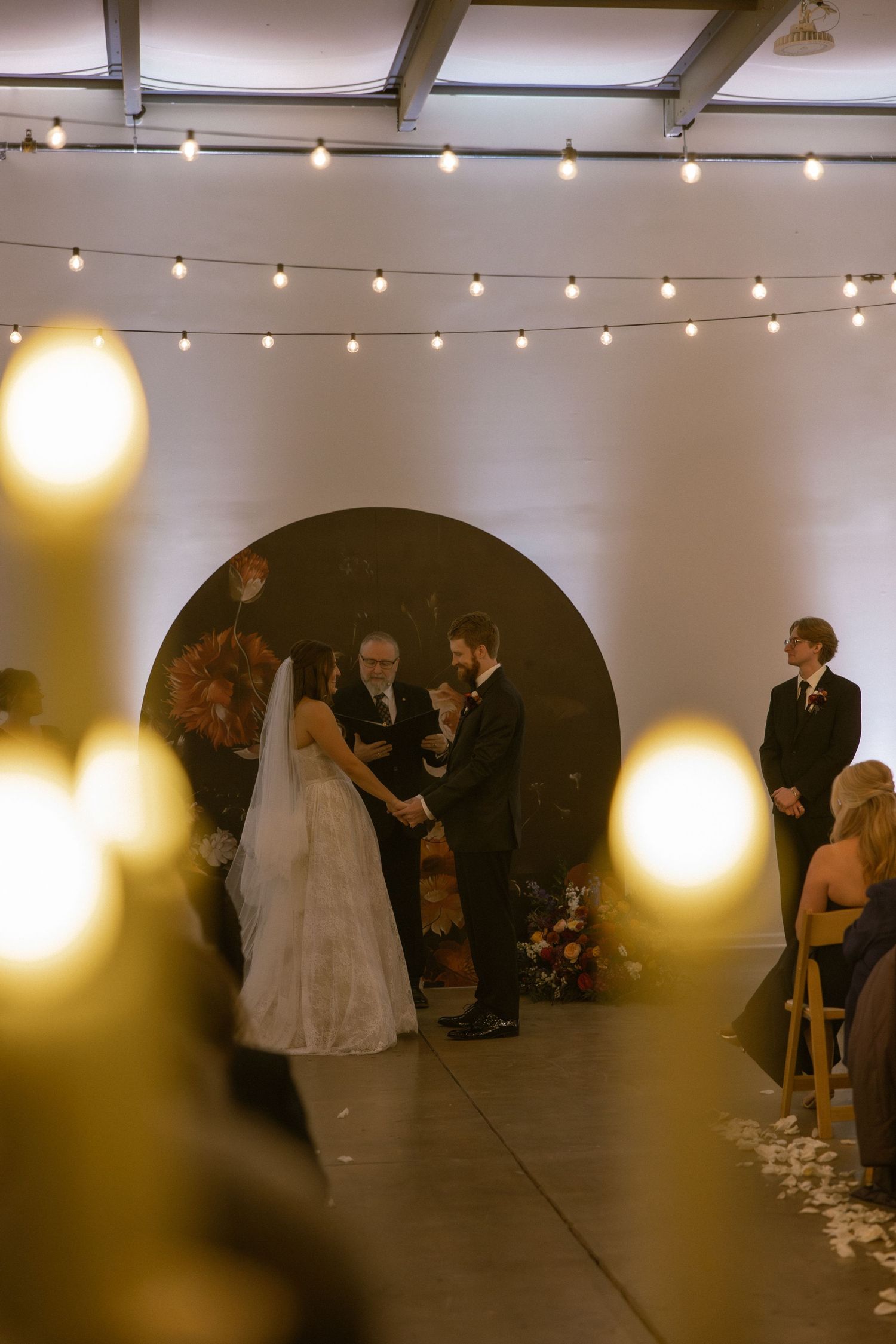 A dimly lit wedding reception venue with string lights and guests creating a moody atmosphere.