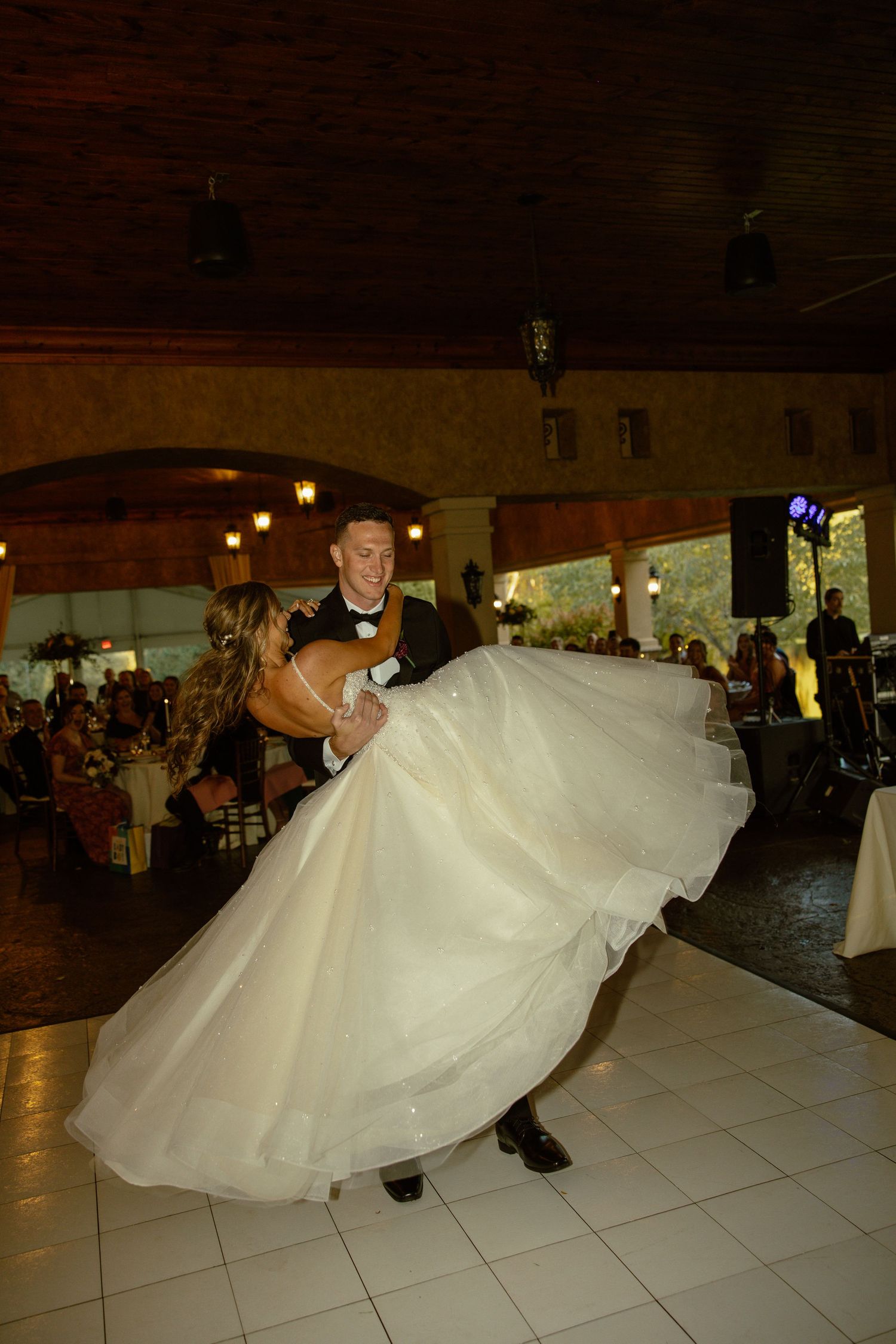 A dramatic dance sequence on a white tiled floor showing the bride's dress twirling in an elegant spin.
