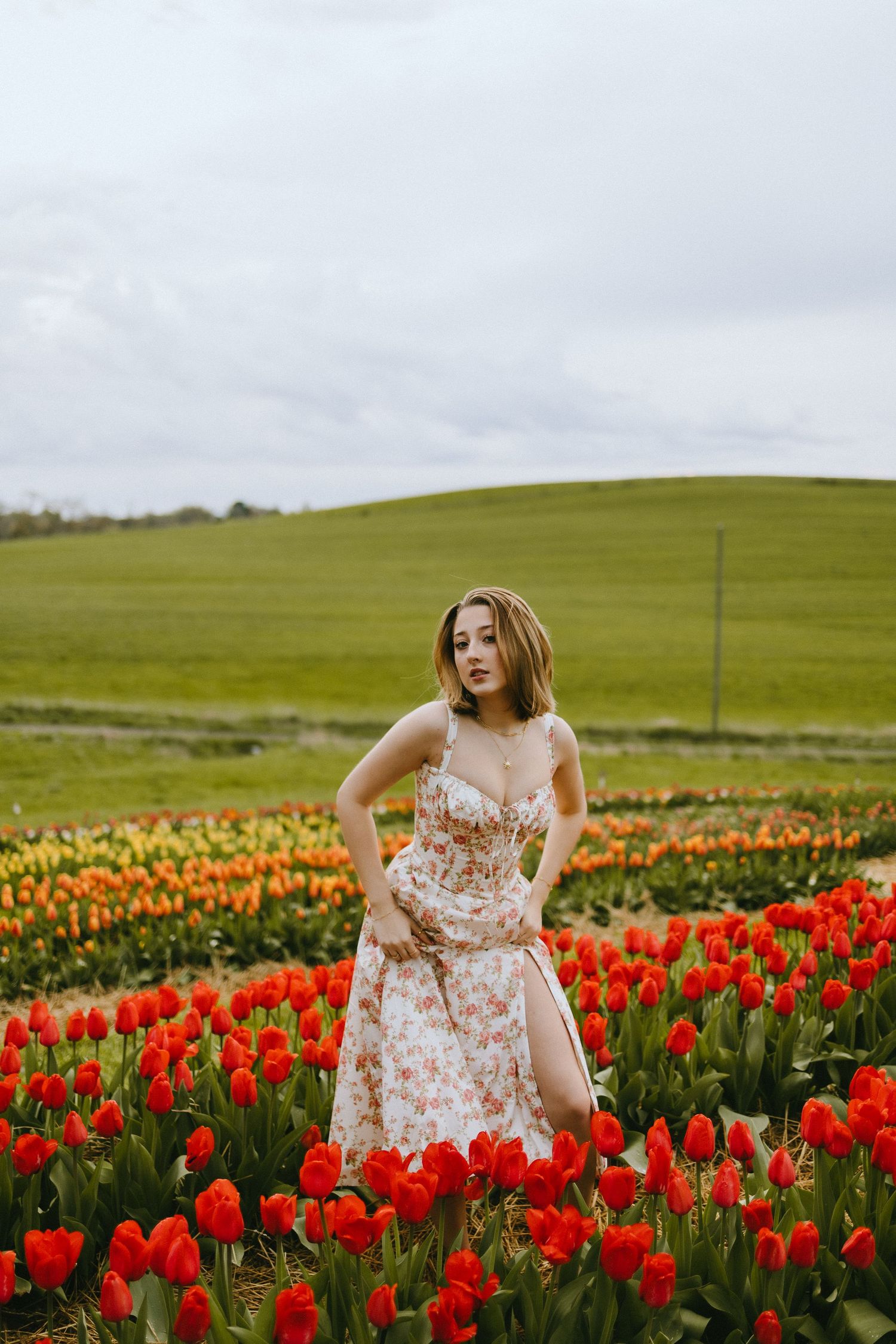 A romantic photo shoot in a blooming tulip field with rolling green hills in the background.