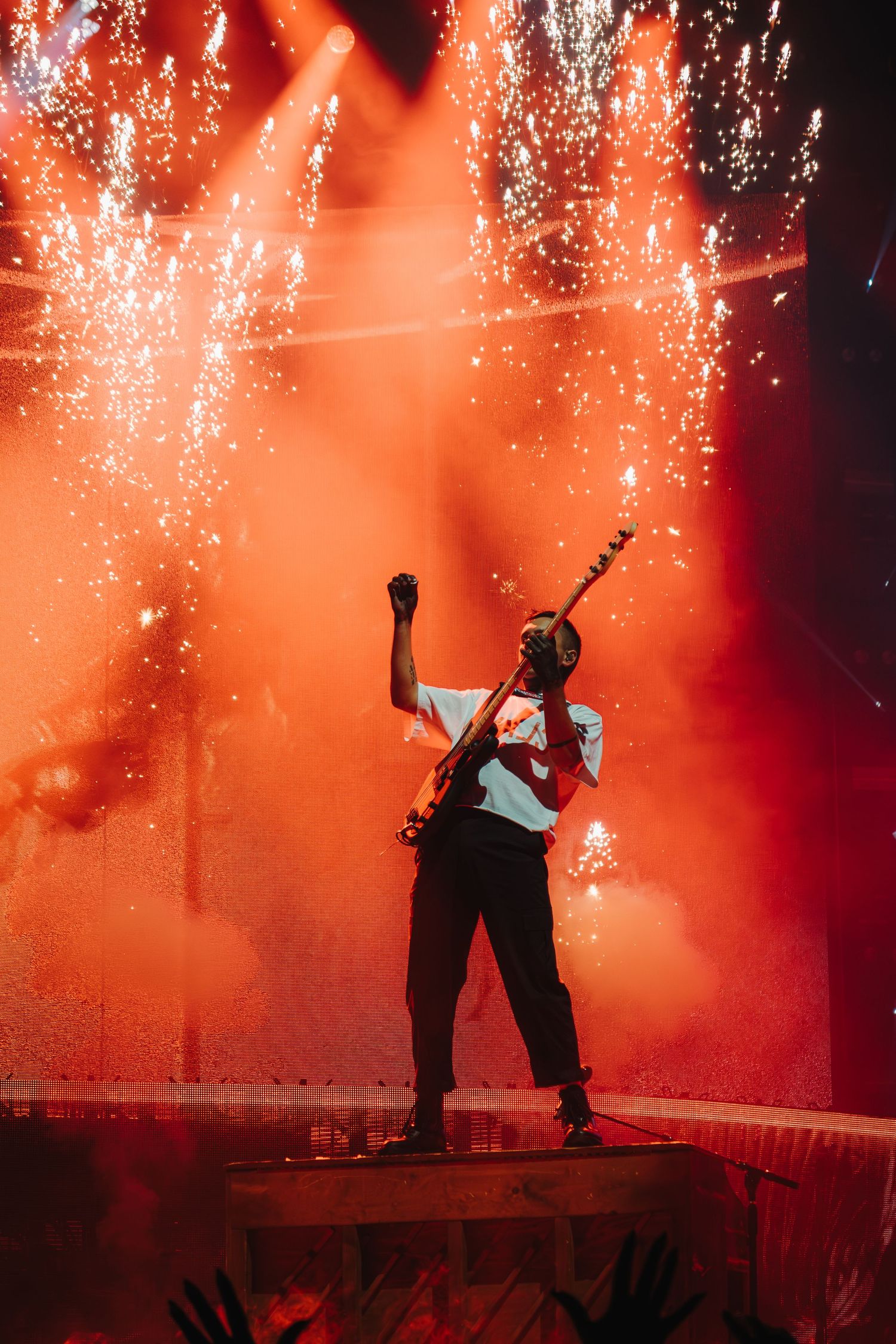 Artist performs on elevated platform with sparkler effects and red lighting.