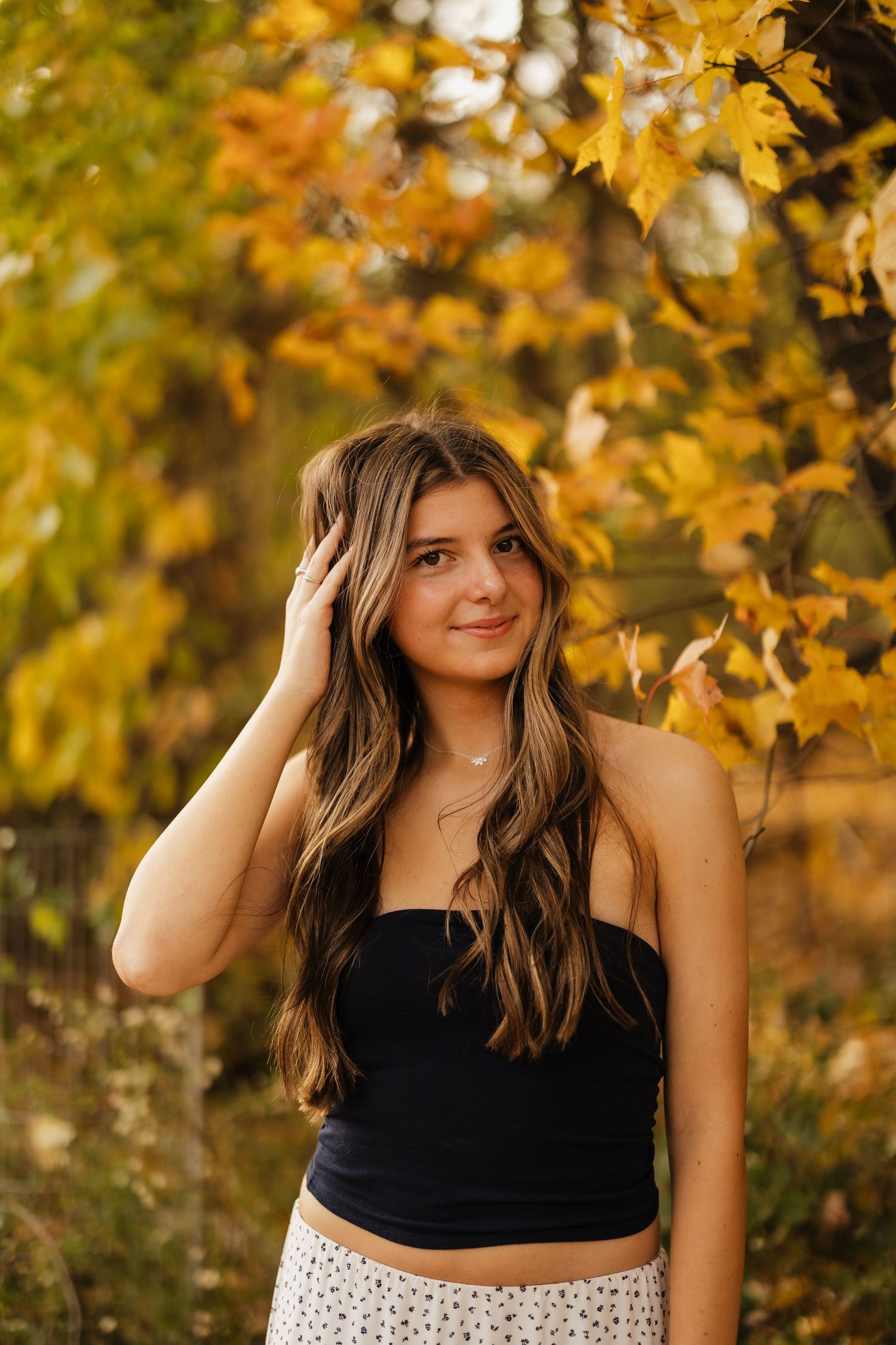 A casual autumn portrait featuring a black top and flowy skirt among golden leaves.