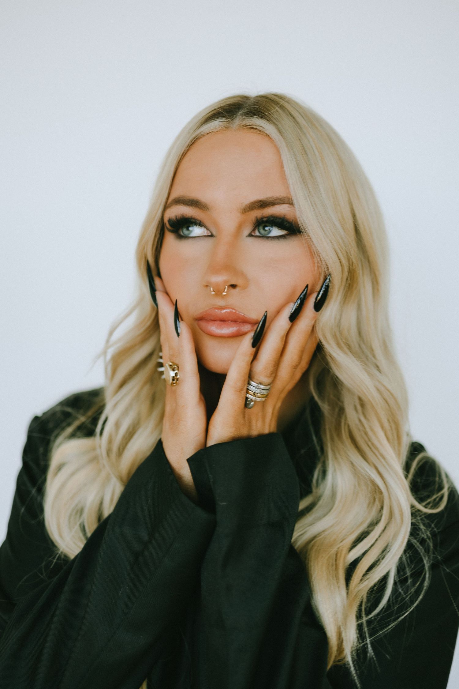 Close-up beauty shot with emerald eye makeup, nude lips and statement rings.