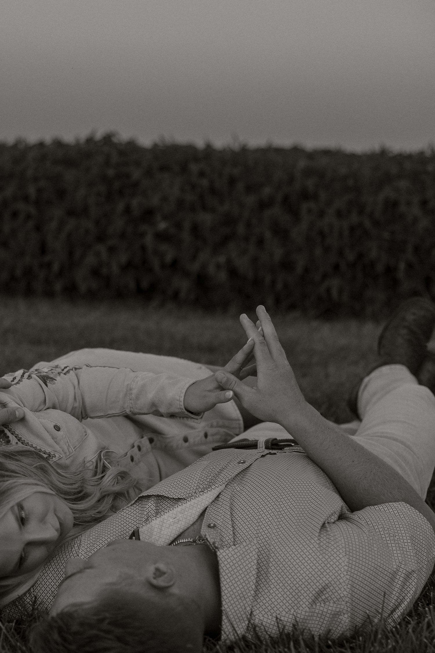 Black and white photograph showing several people lying down in a field with trees visible in the background.
