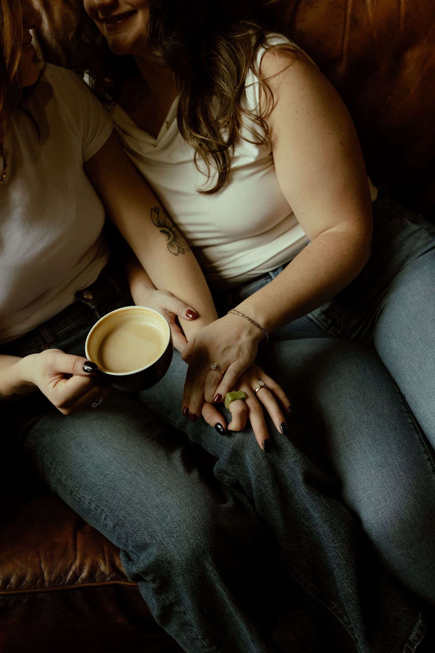 Person in gray pants sits holding a white coffee mug in moody lighting against a dark background.