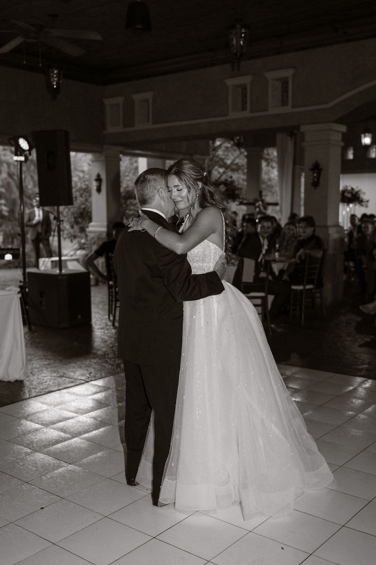 Black and white photos capture an intimate first dance moment at an indoor wedding reception.