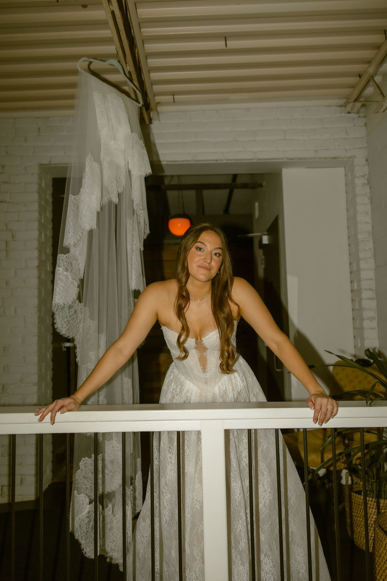 A sequence of candid shots showing a bride in a white dress leaning over a white railing at dusk.