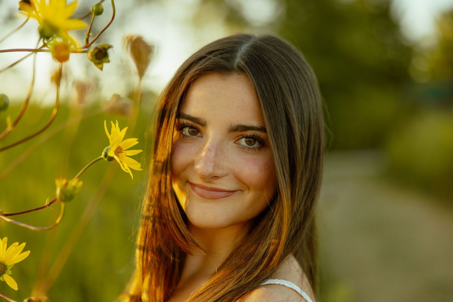 A golden sunset illuminates yellow wildflowers in a dreamy outdoor portrait scene.