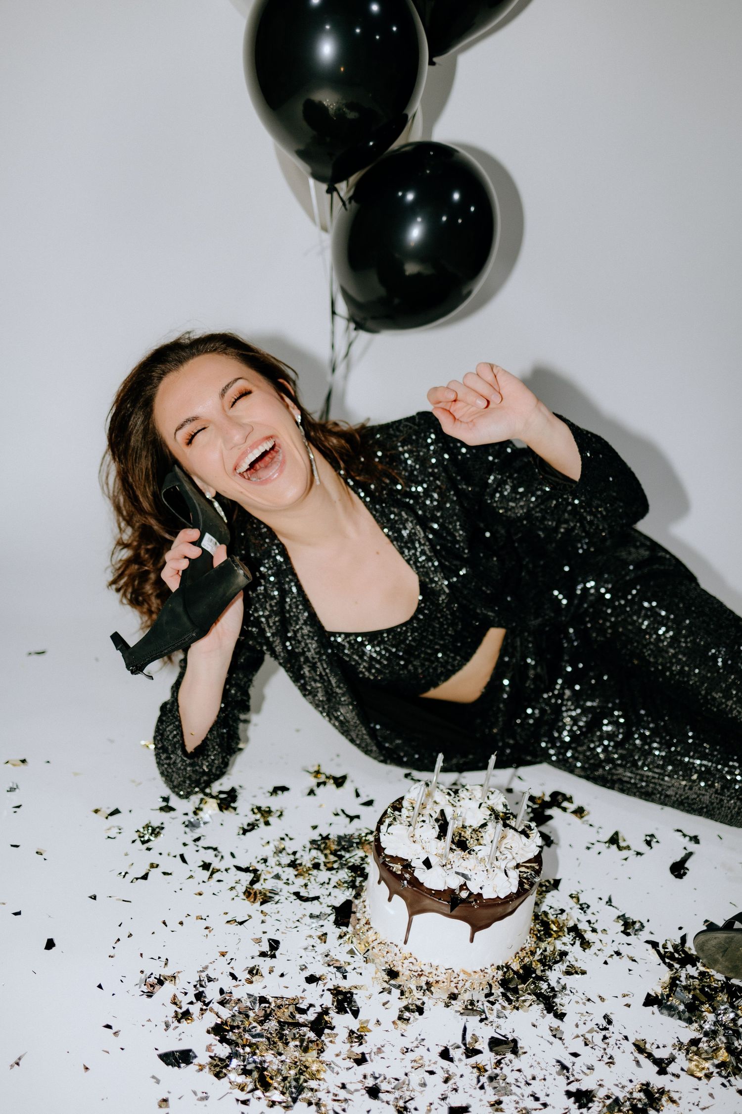 Celebration scene with black balloons, sparkly outfit and smashed cake.