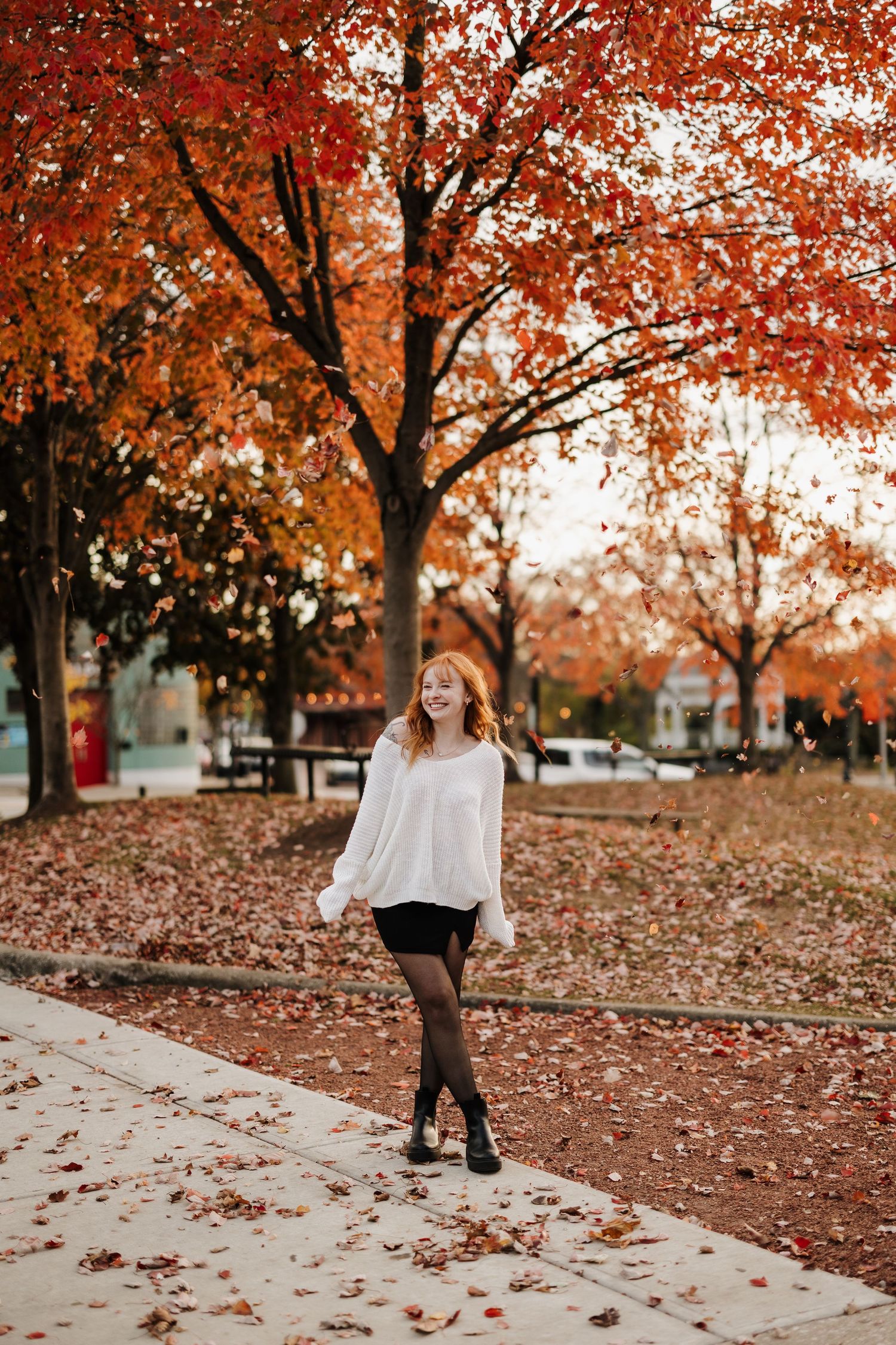 Autumn fashion photo with vibrant orange fall foliage and white sweater.