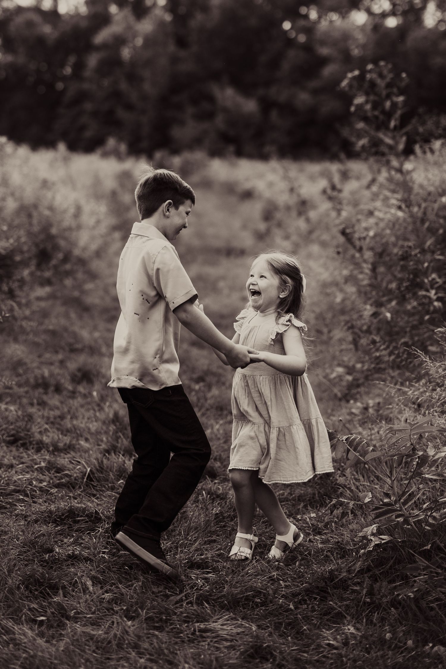 Black and white photo of children dancing and laughing together on a nature trail.