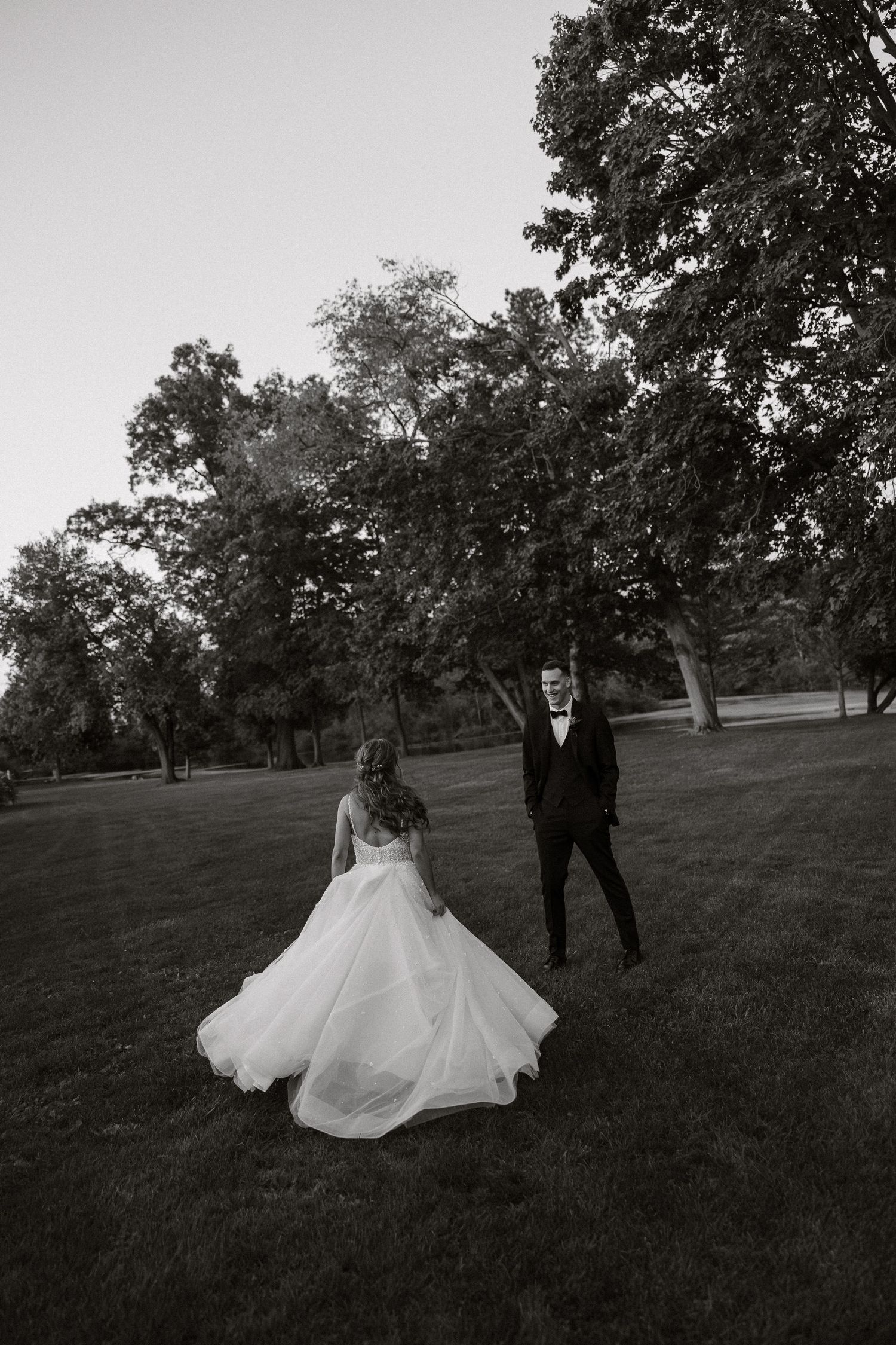 Black and white wedding portrait with flowing dress on rolling hillside.