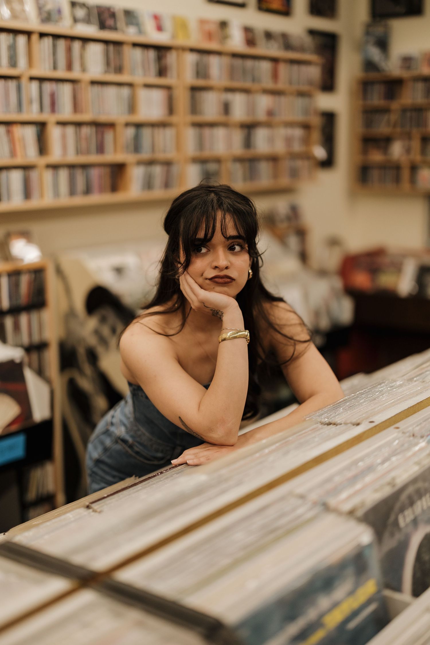 Person browsing through vinyl records in a room with extensive bookshelves.