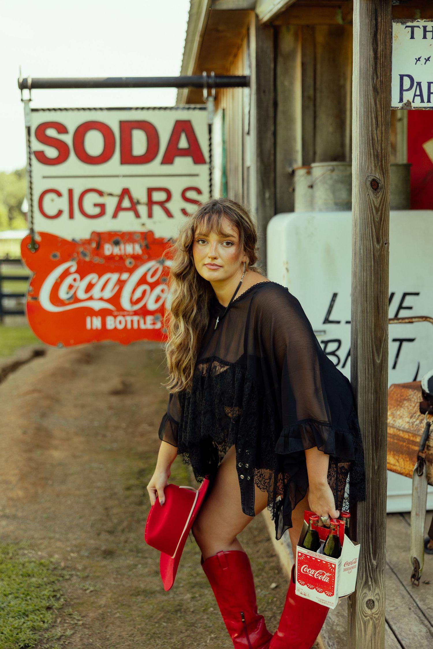A vintage-style scene with a black shirt and red boots against rustic Coca-Cola signs and wooden walls.