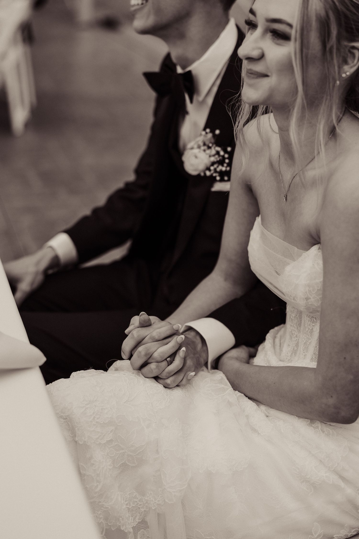 A tender black and white wedding moment showing a couple holding hands during their ceremony.