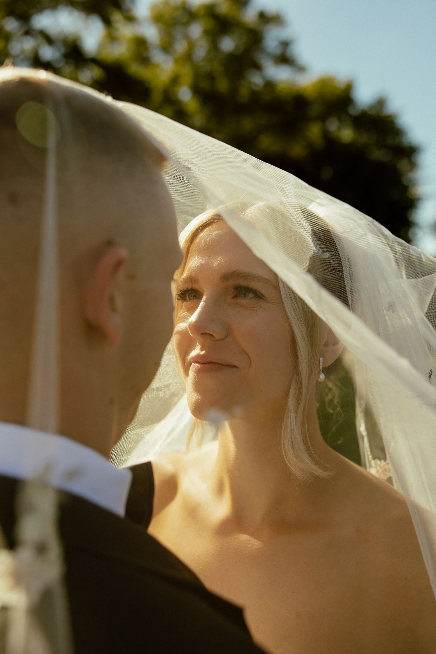 Close-up shot of bridal veil flowing in sunlight against blue sky.