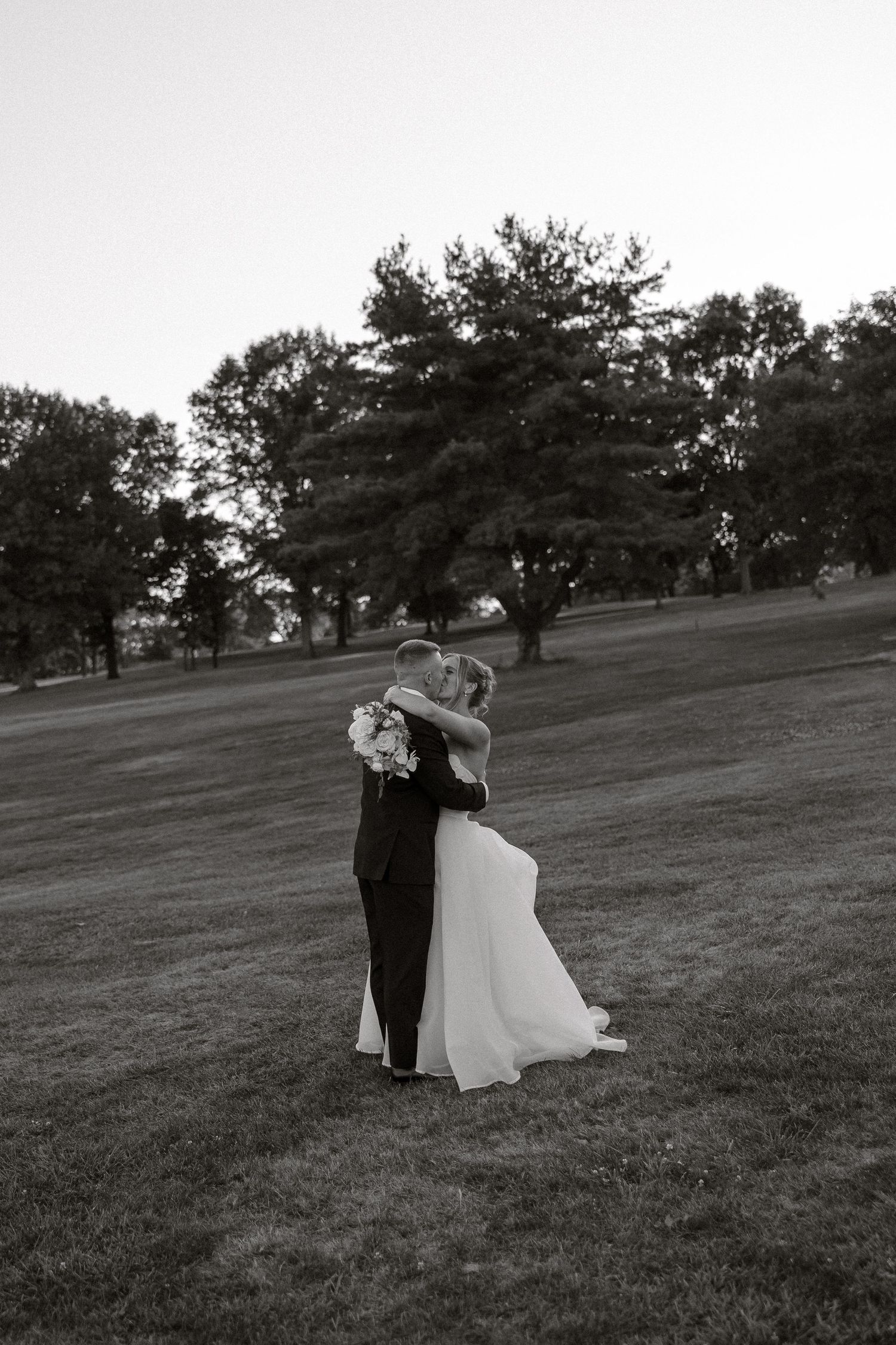Black and white photo sequence of a couple dancing in an open field with trees in the background.