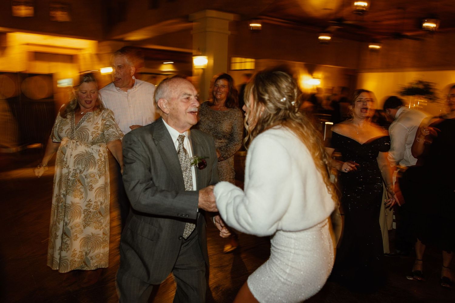 Blurred motion shots of people dancing and celebrating at an evening wedding reception.