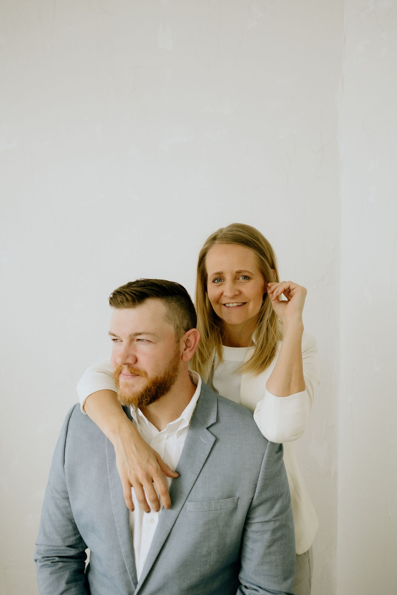 Casual professional portrait of two people against white background in modern setting.