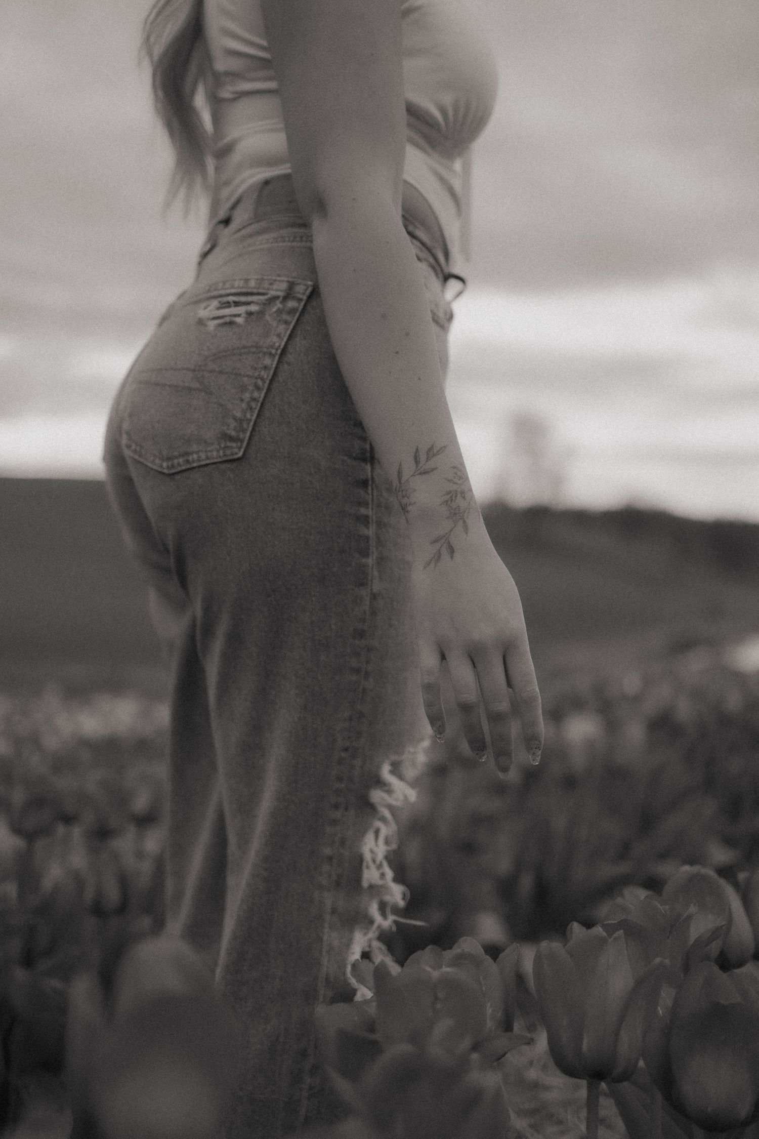 Black and white artistic photo of person in denim against dramatic sky.
