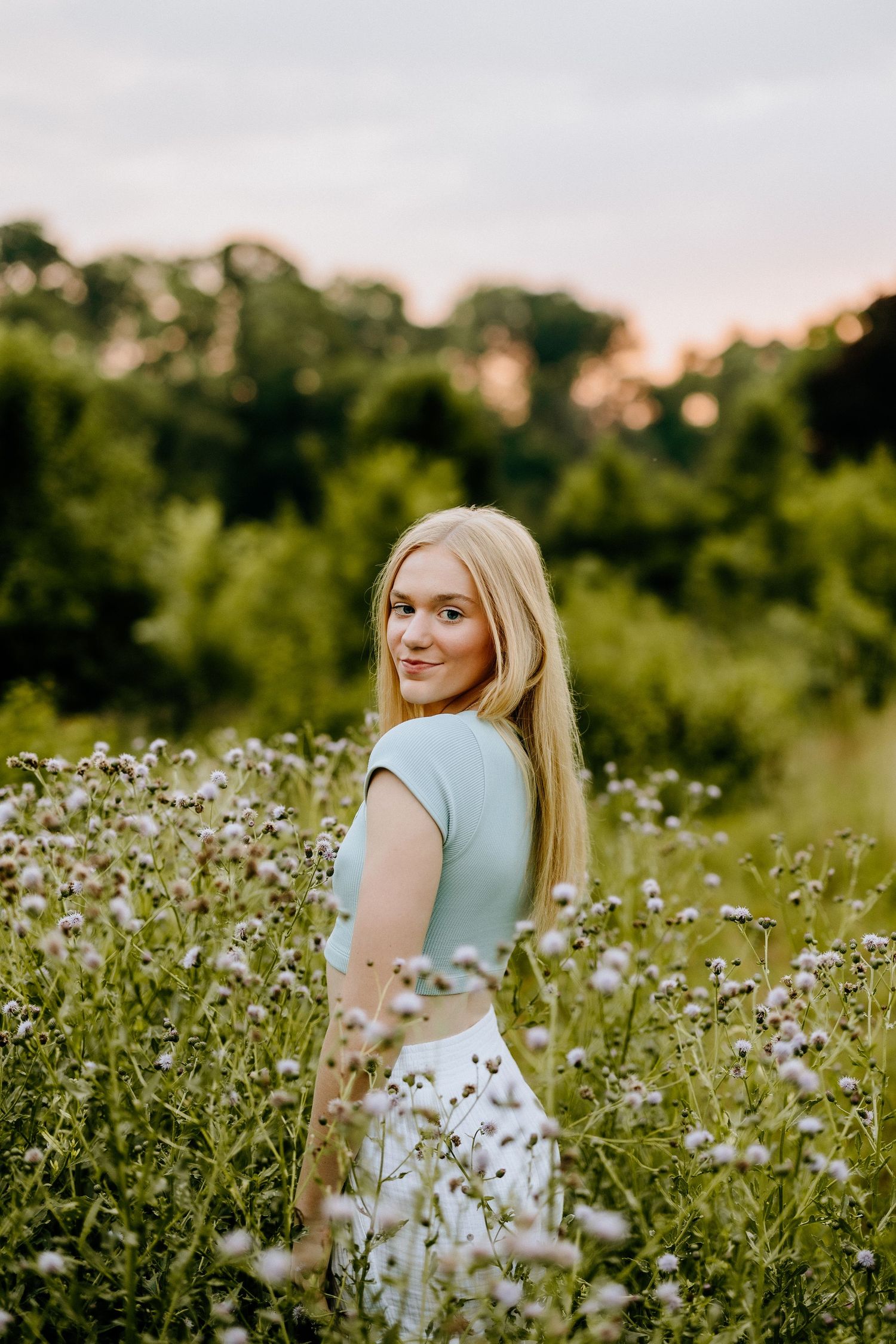 Dreamy portrait in wildflower field wearing mint green top at sunset.