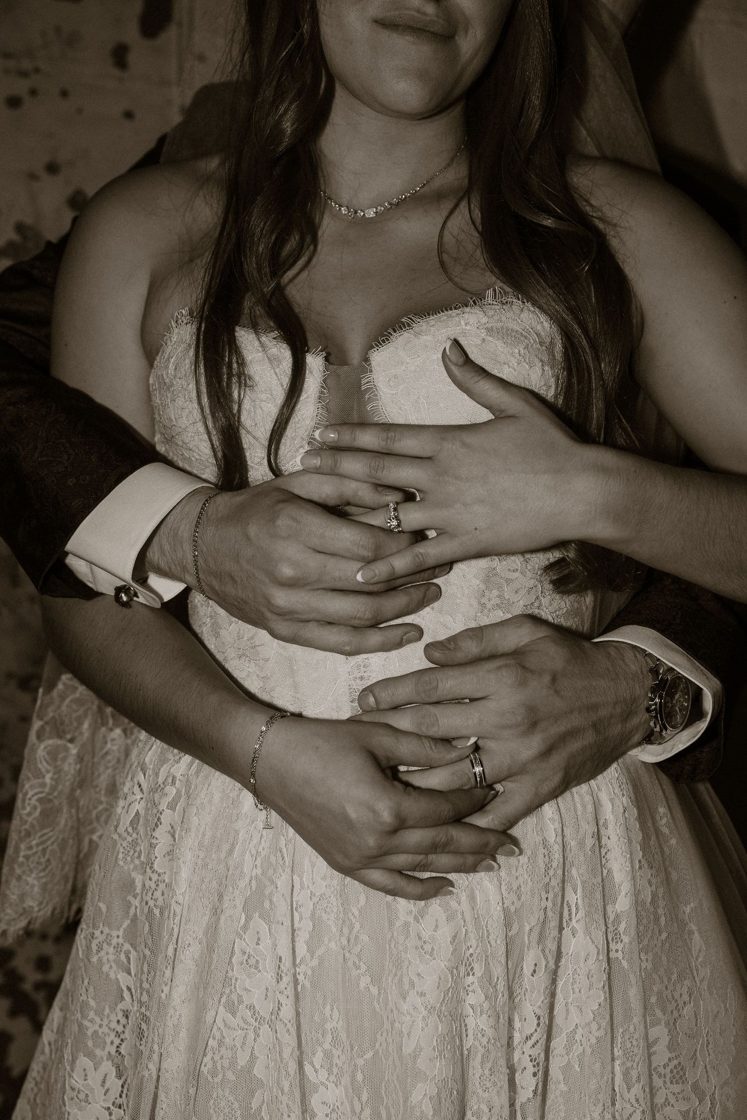 Close-up sequence of hands with rings on white lace wedding dress fabric.