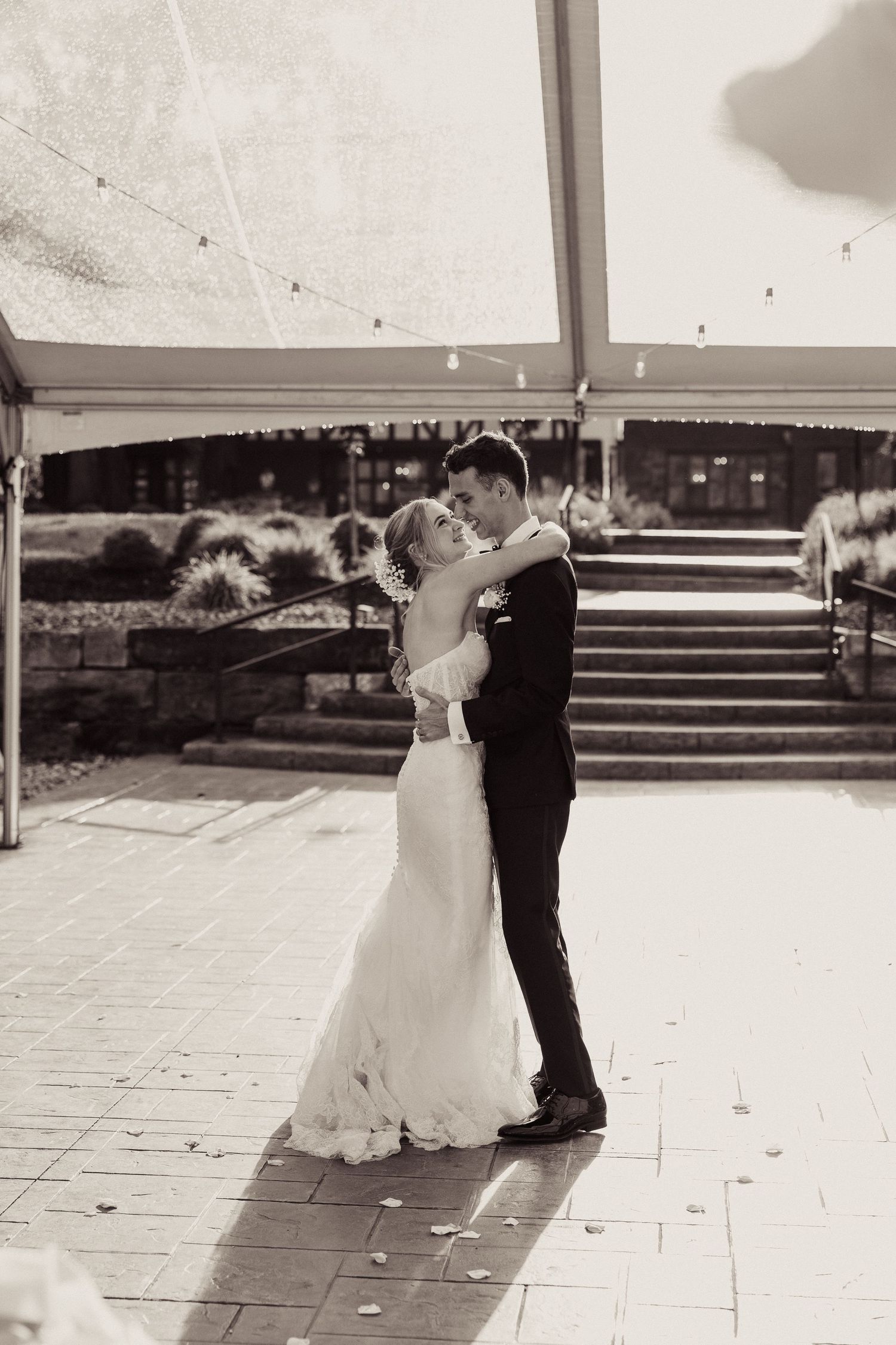 A romantic black and white sequence shows a couple dancing together on an outdoor patio during their wedding celebration.