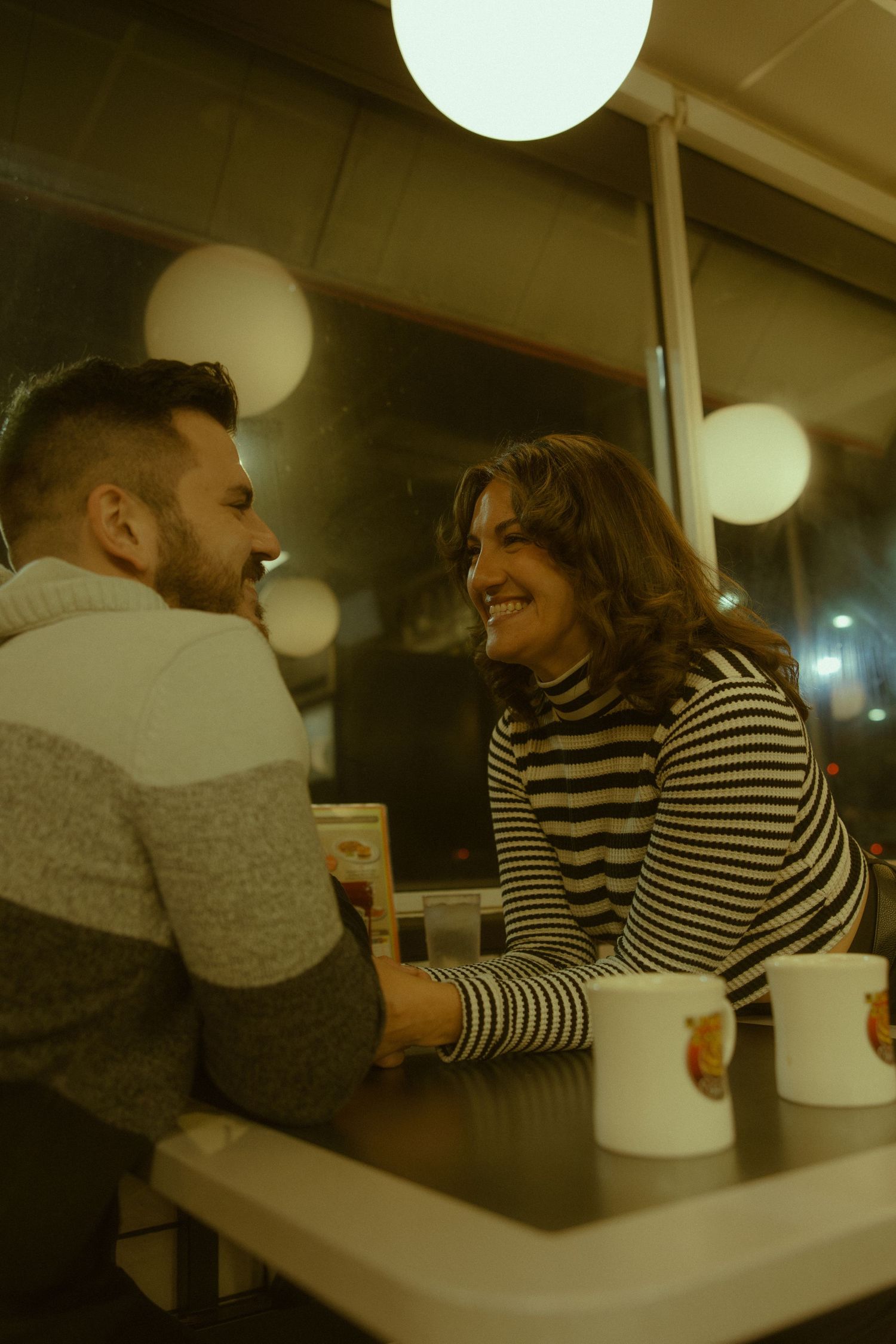 Diners enjoying conversation at a casual restaurant booth with modern lighting and striped patterns visible.