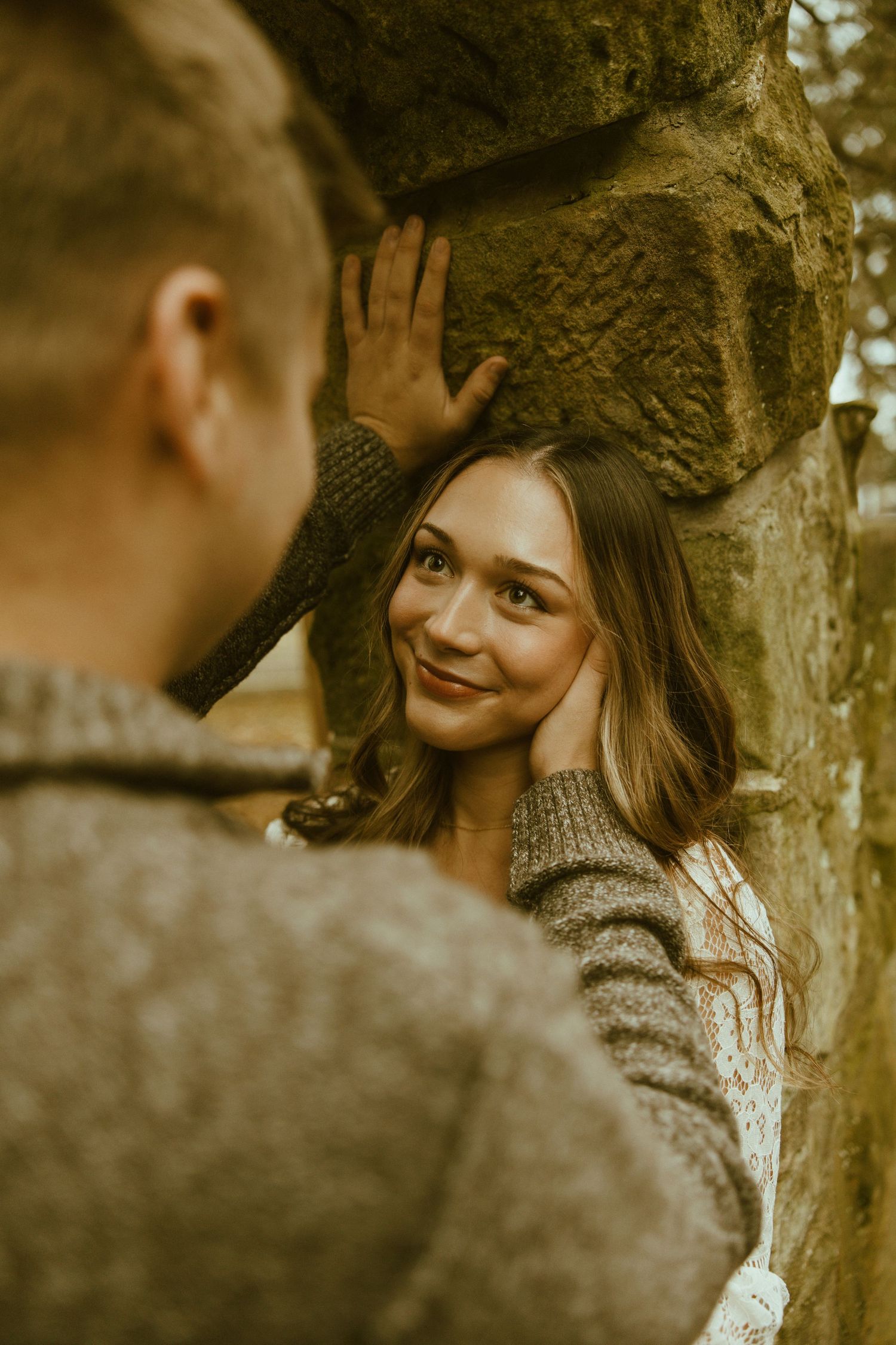 A romantic couple sharing intimate moments in a sepia-toned outdoor photoshoot against a tree.