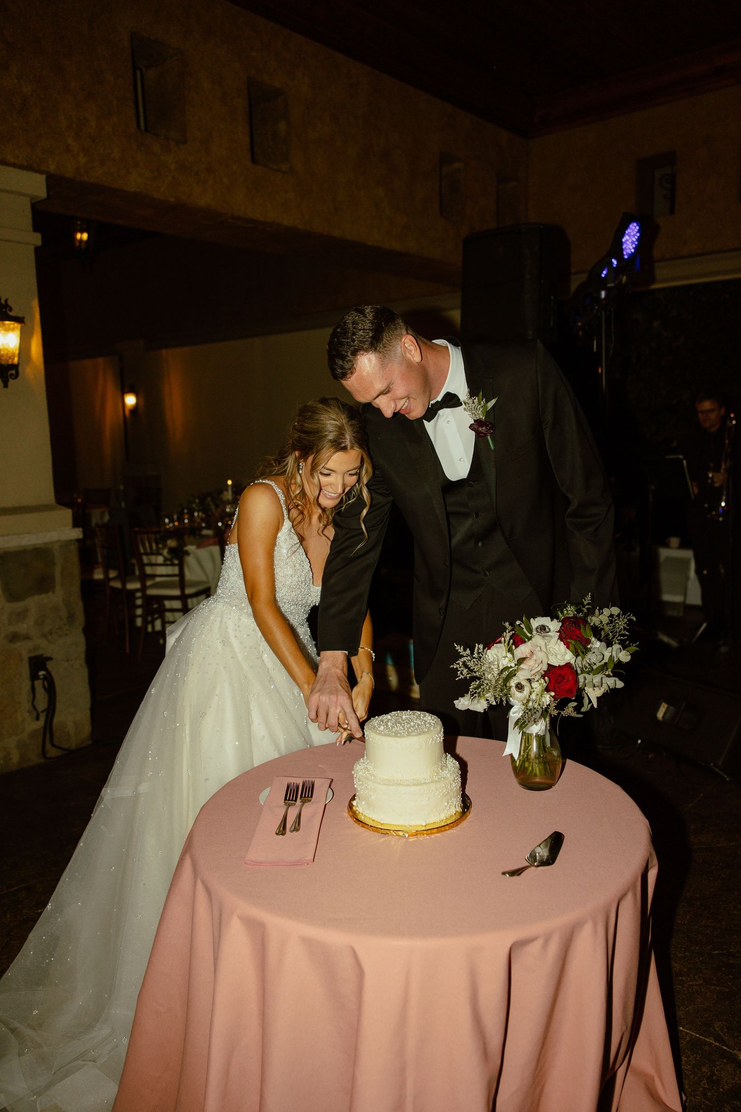 A couple shares a sweet moment while cutting their wedding cake at their reception.