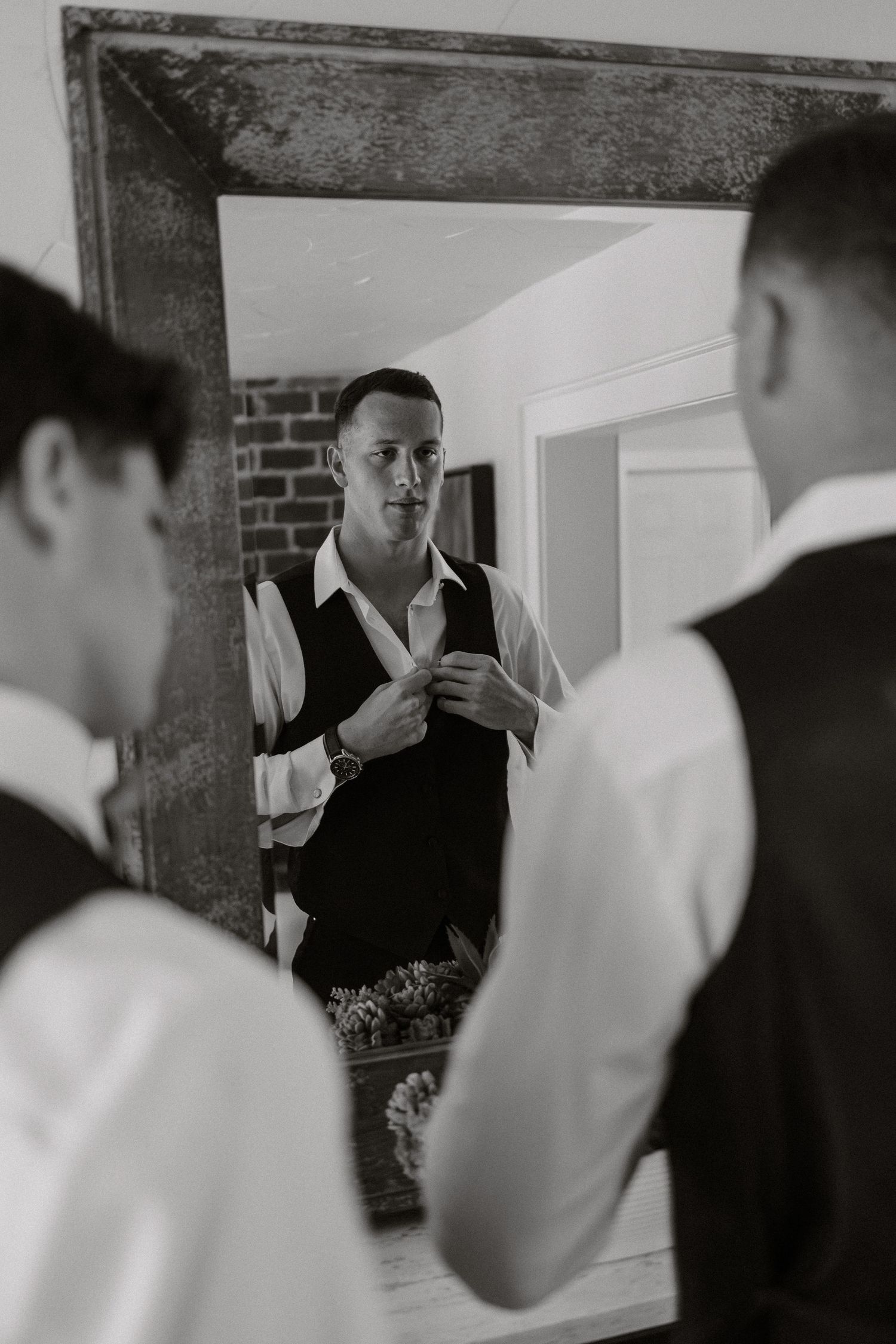 A black and white photograph showing wedding preparations reflected in a mirror.