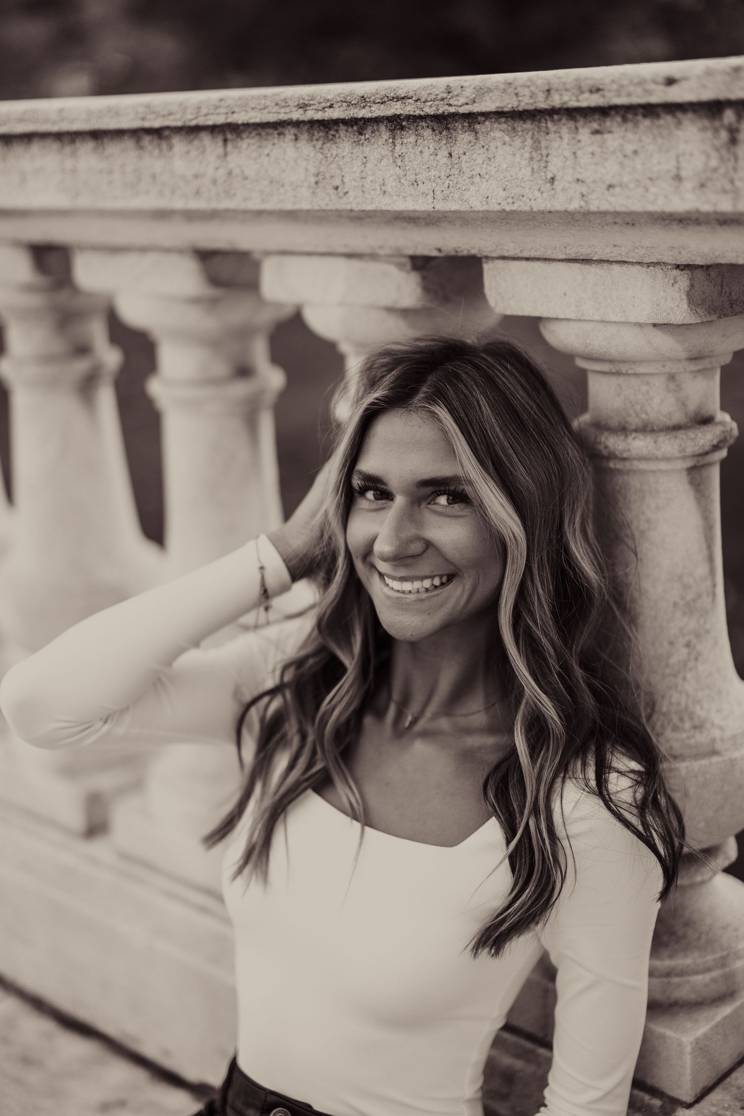 A black and white portrait shows someone smiling against classic stone architecture.