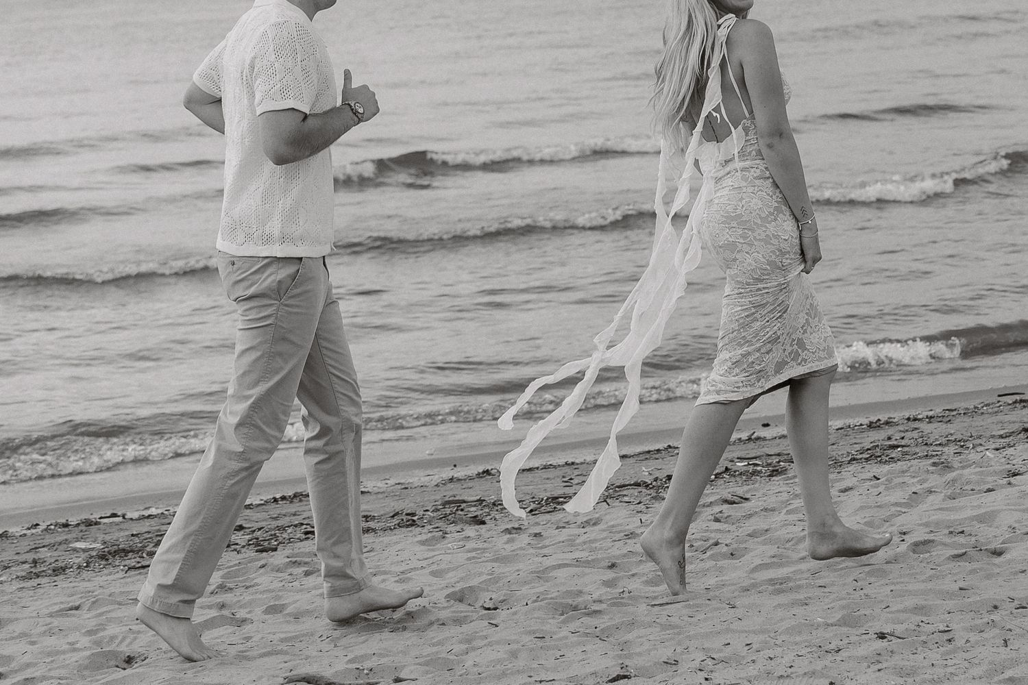 A black and white sequence shows people walking along a beach shore with their feet in the water.