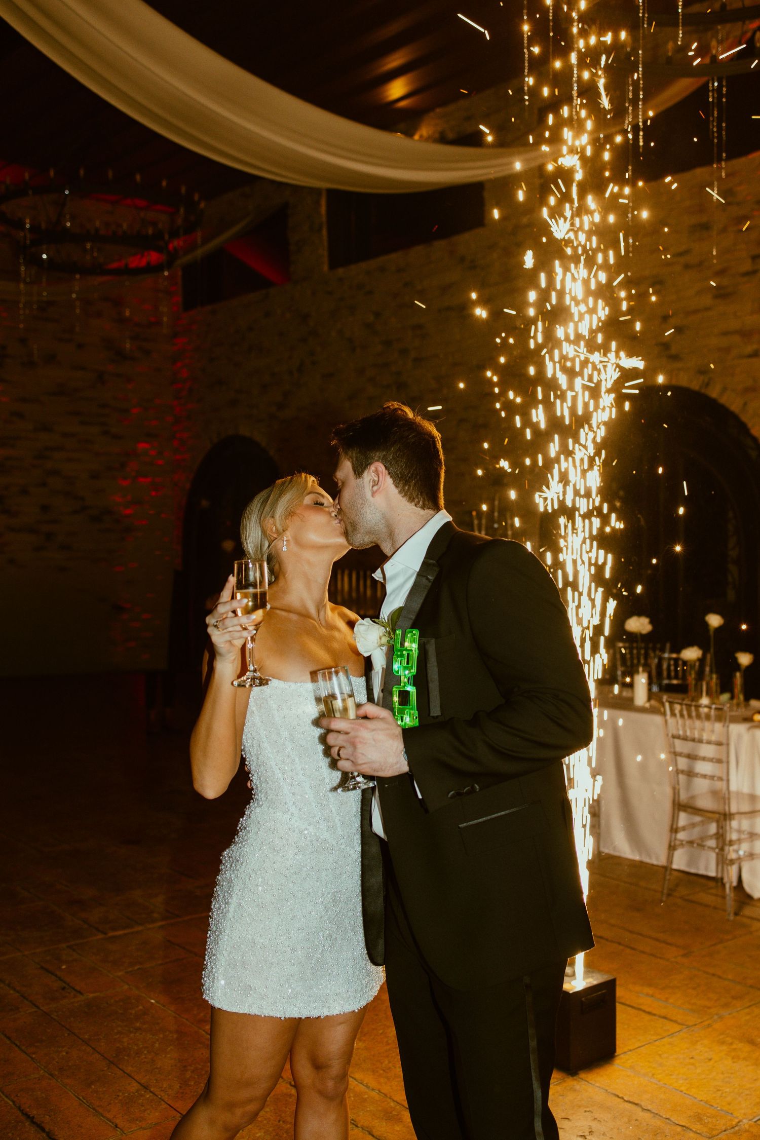 First dance moment under cascading sparkler lights in rustic venue with dramatic lighting.