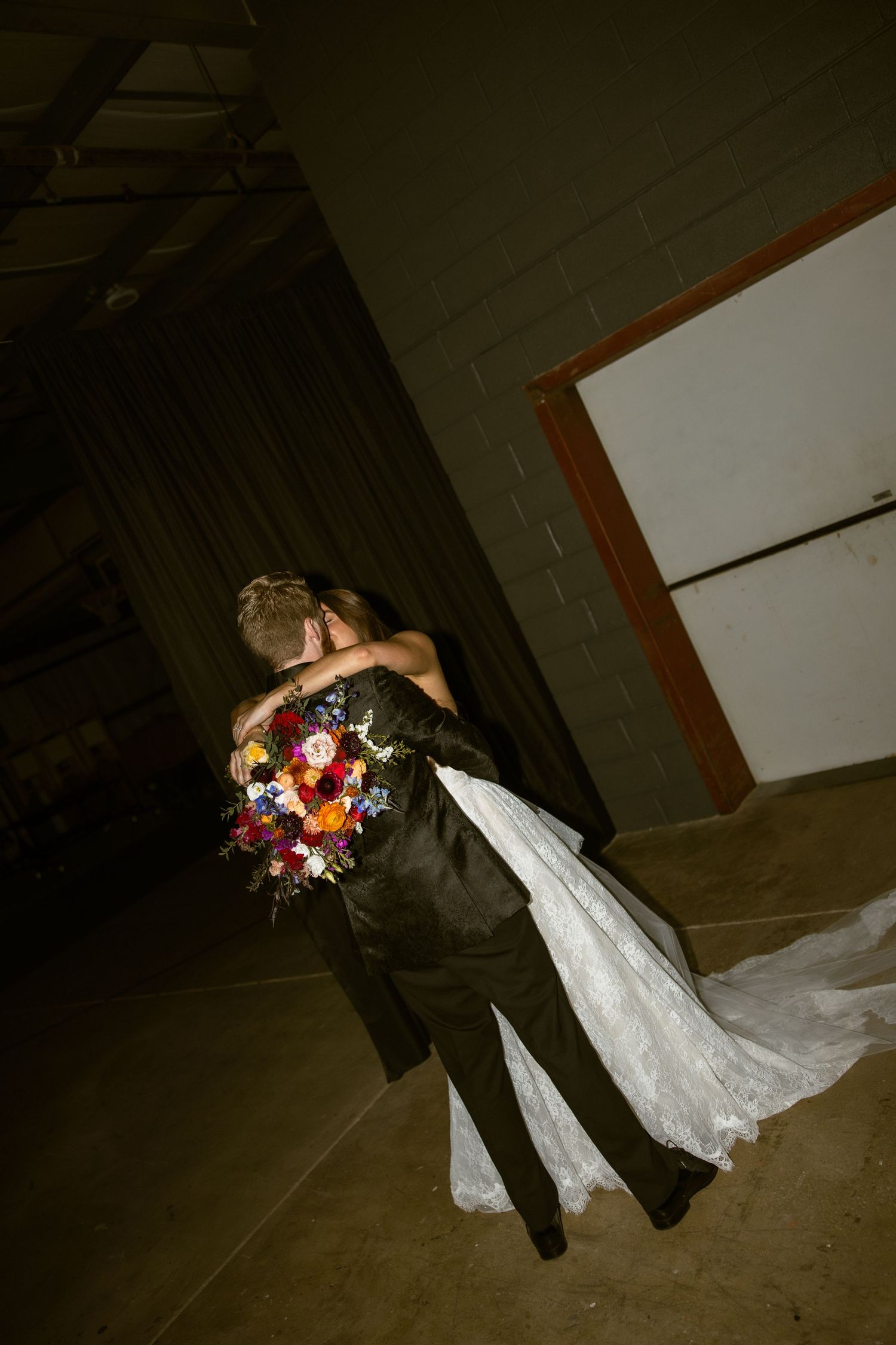 Artistic silhouette of newlyweds dancing together in a dimly lit venue.