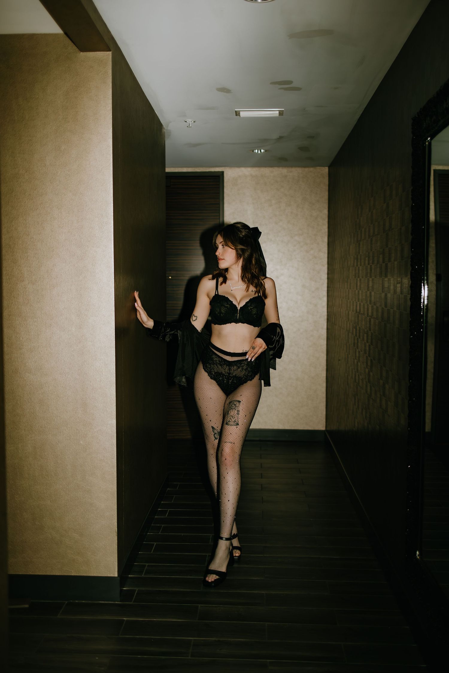 Dark hallway fashion photo in black lingerie and sheer stockings.