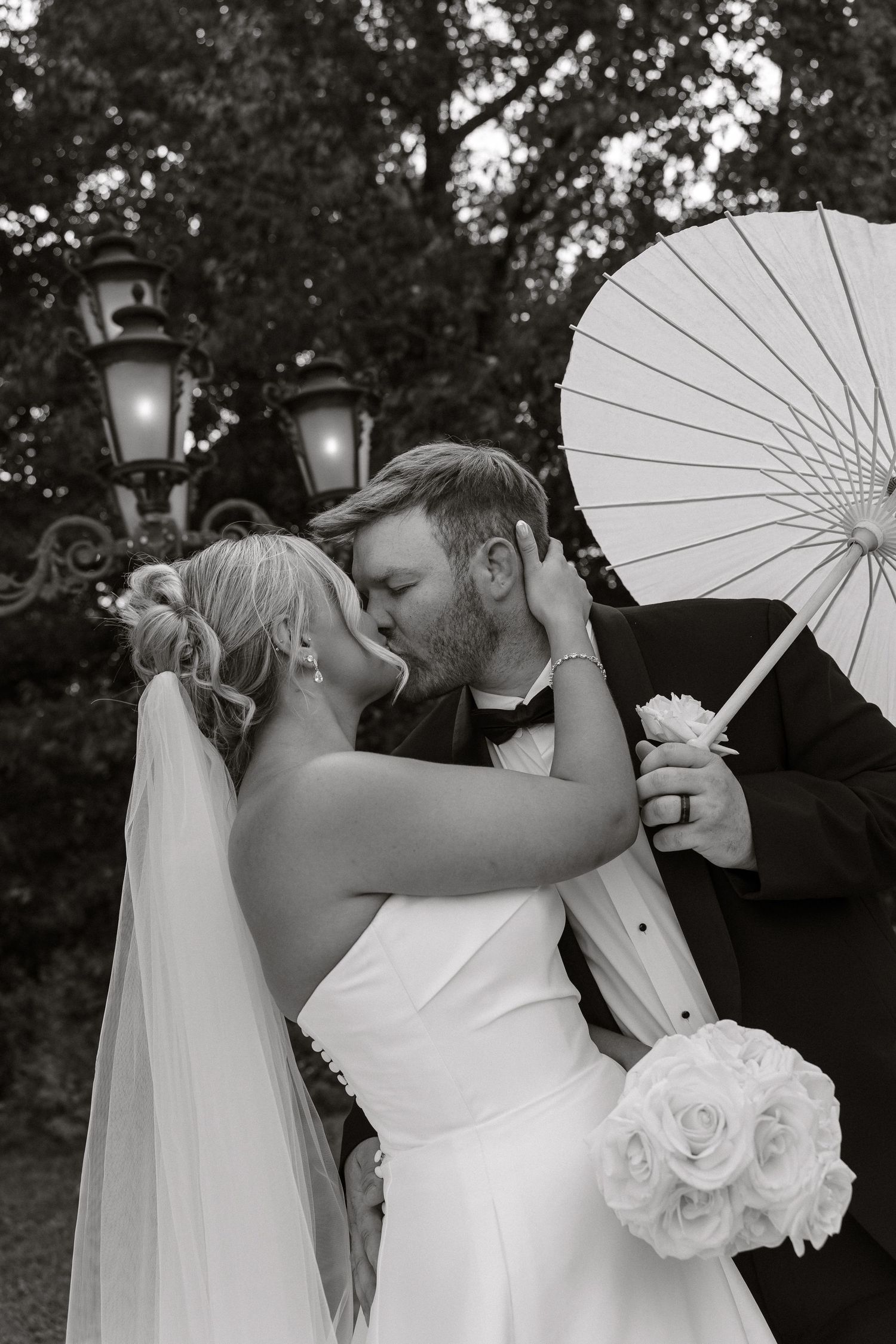 A romantic black and white wedding photo series showing a couple sharing intimate moments under a white parasol.