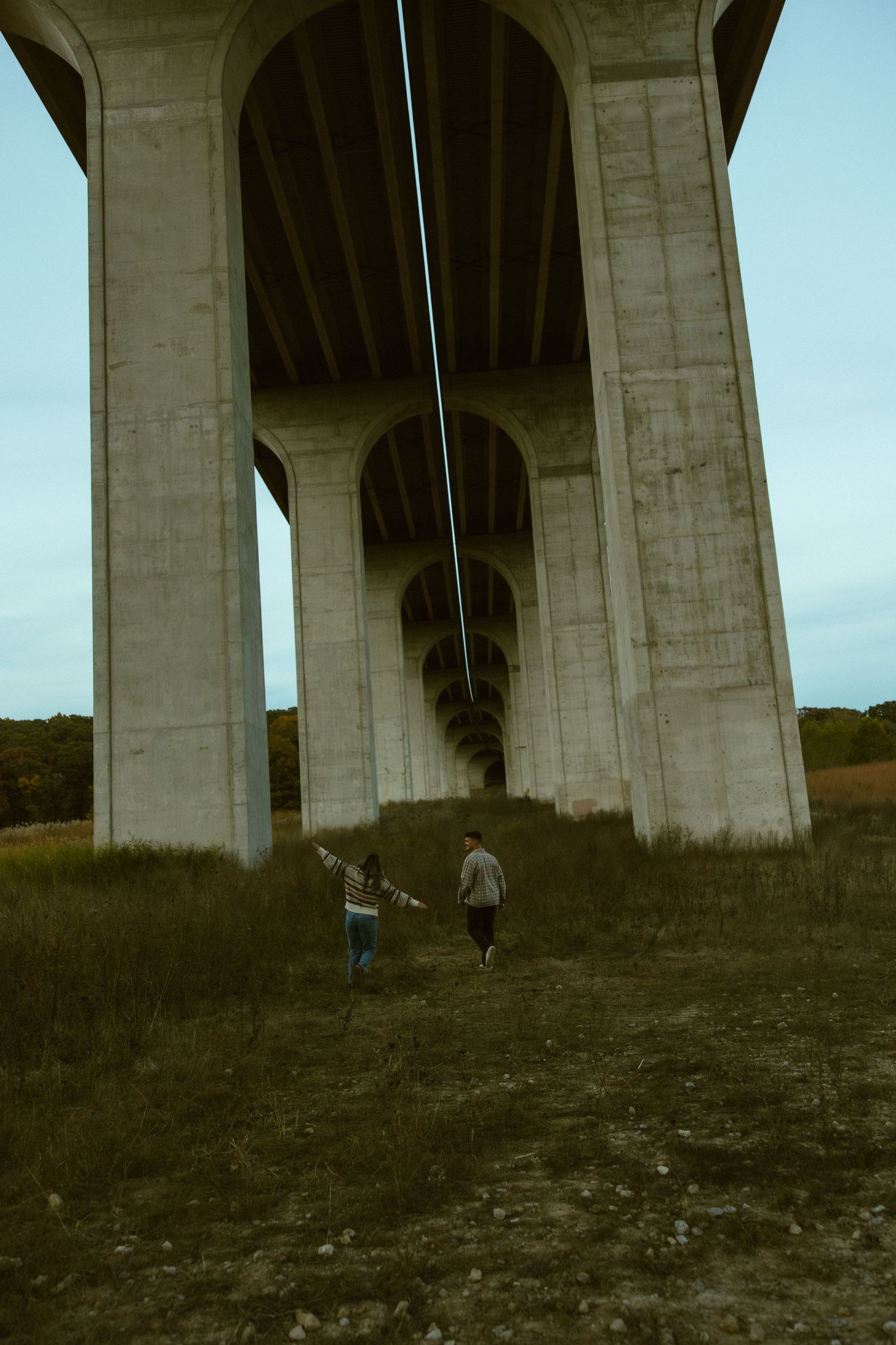 Series of concrete bridge supports or pillars photographed from below against a light blue sky.