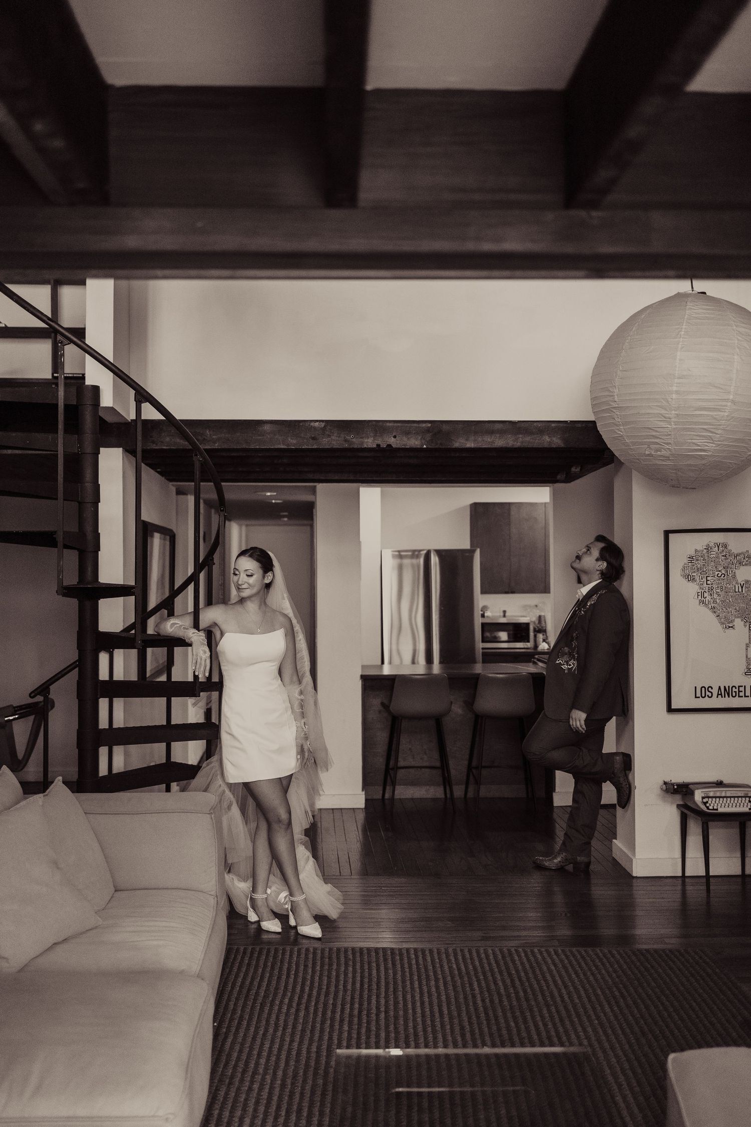 Interior scene with spiral staircase and white paper lanterns hanging from wooden beams.